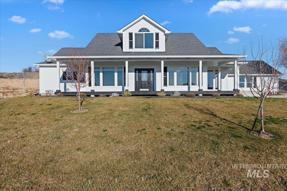 Farmhouse with covered porch, a front lawn, and a shingled roof