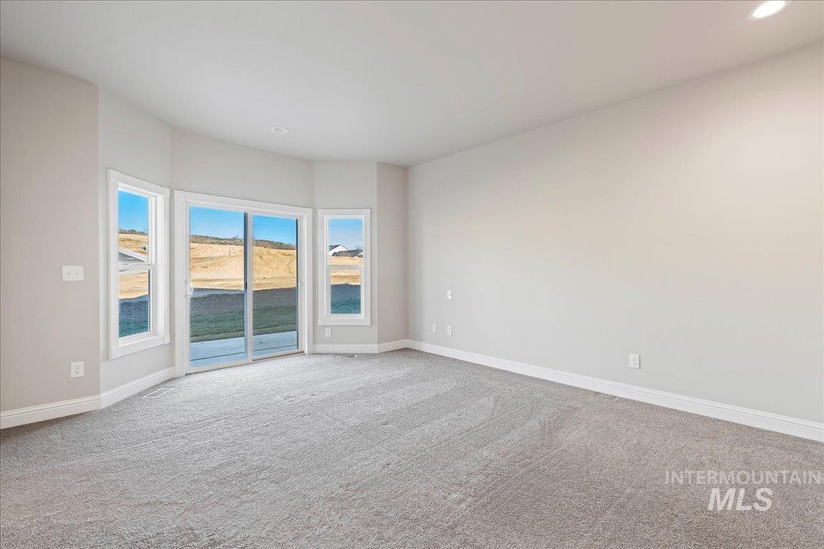 Empty room featuring light carpet, a water view, and recessed lighting