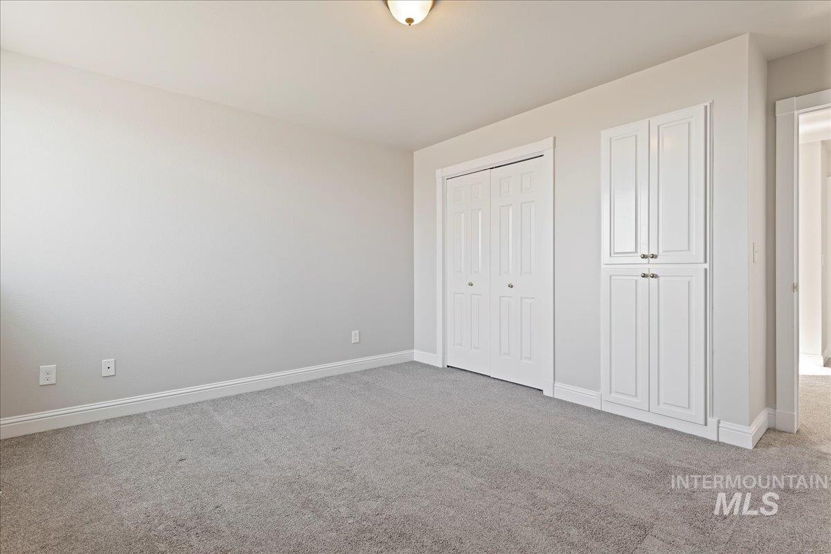 Unfurnished bedroom with light colored carpet and a closet