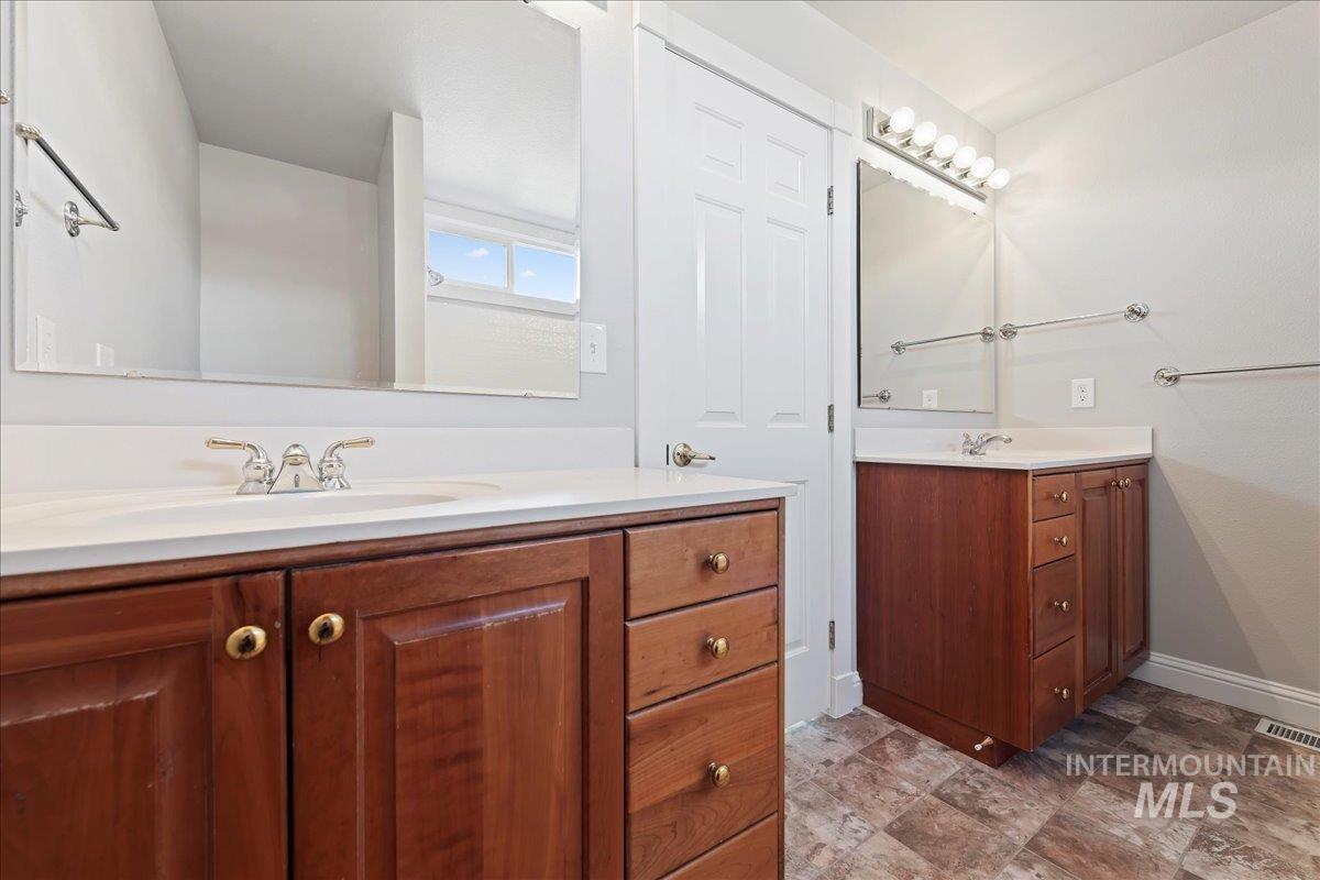 Full bath with two vanities and stone finish floors