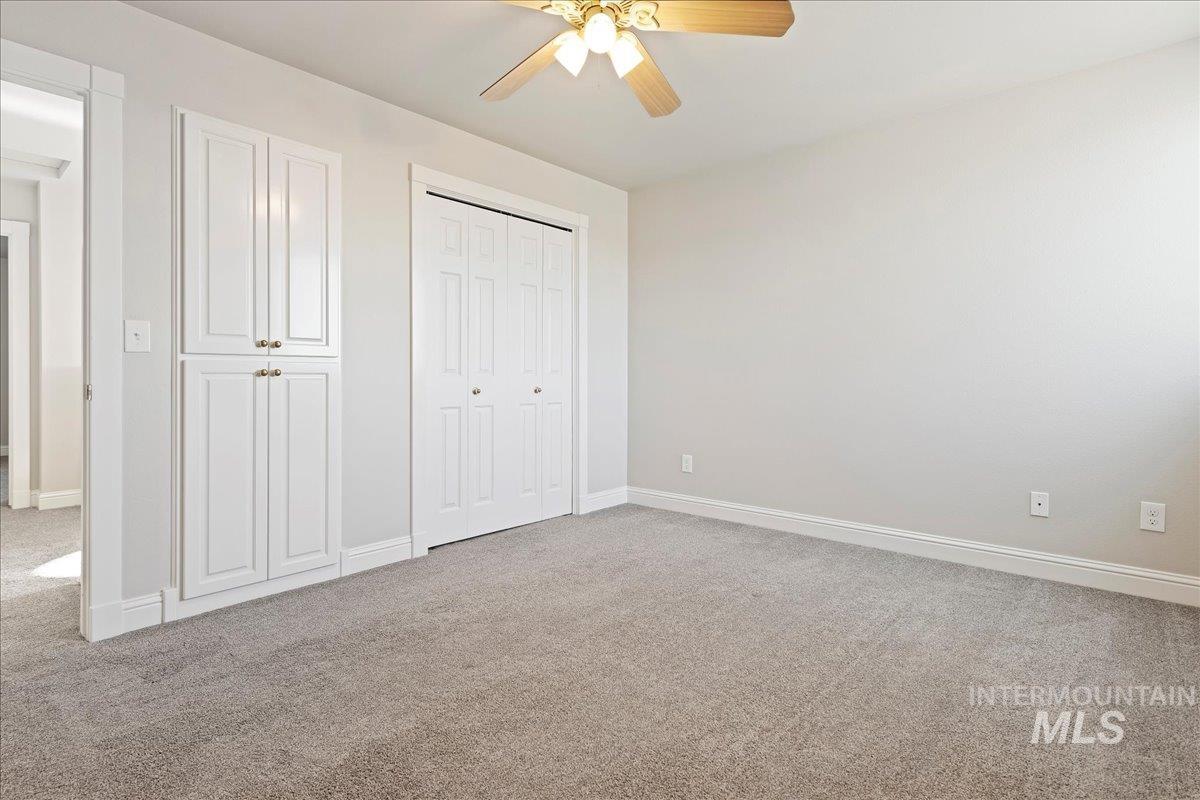 Unfurnished bedroom featuring light colored carpet, ceiling fan, and a closet