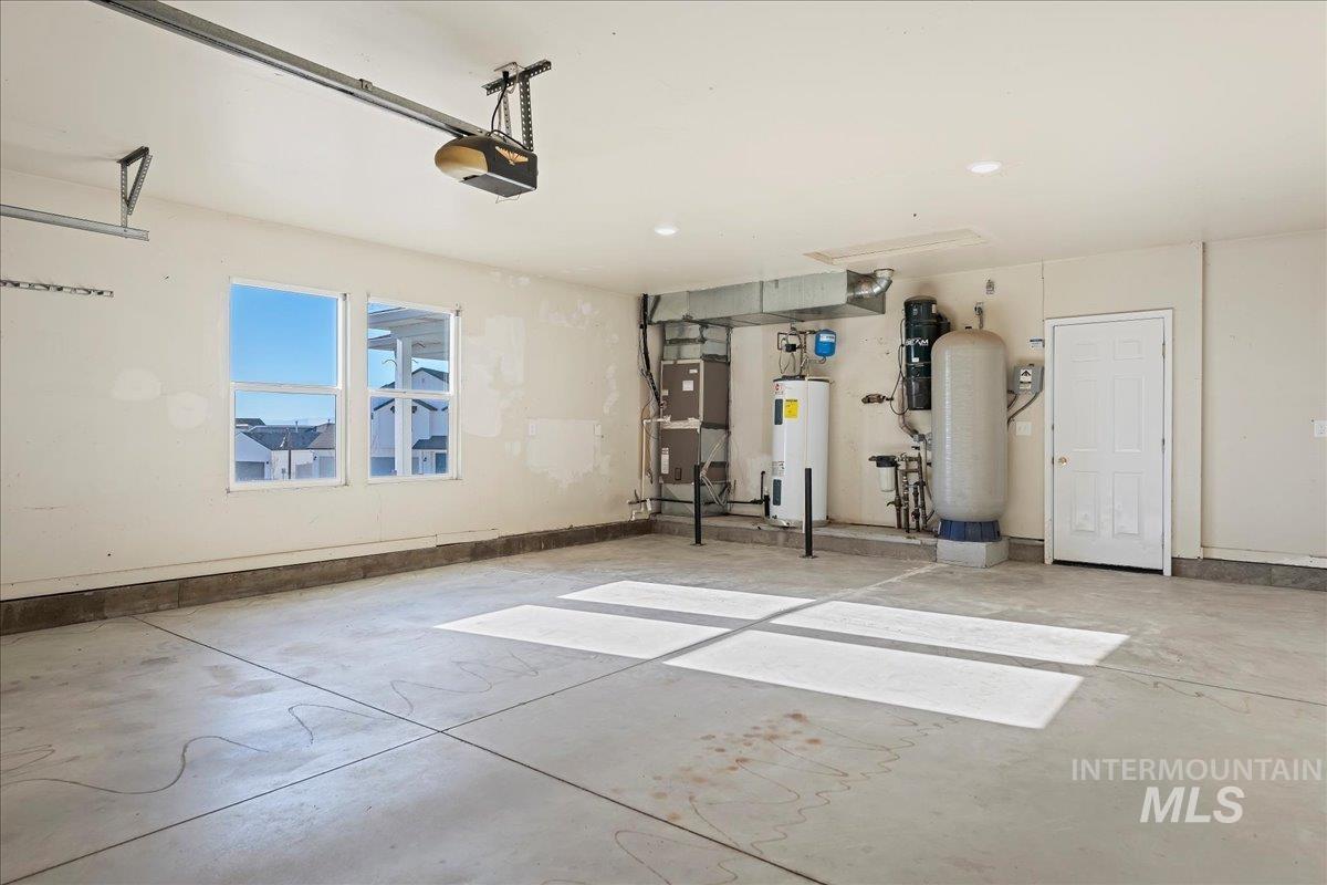 Garage featuring heating unit, water heater, and a garage door opener