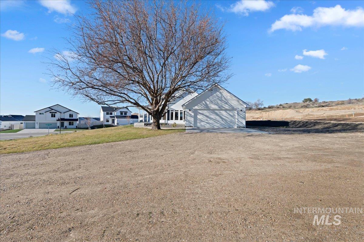 View of front of house with dirt driveway, a garage, and a front lawn
