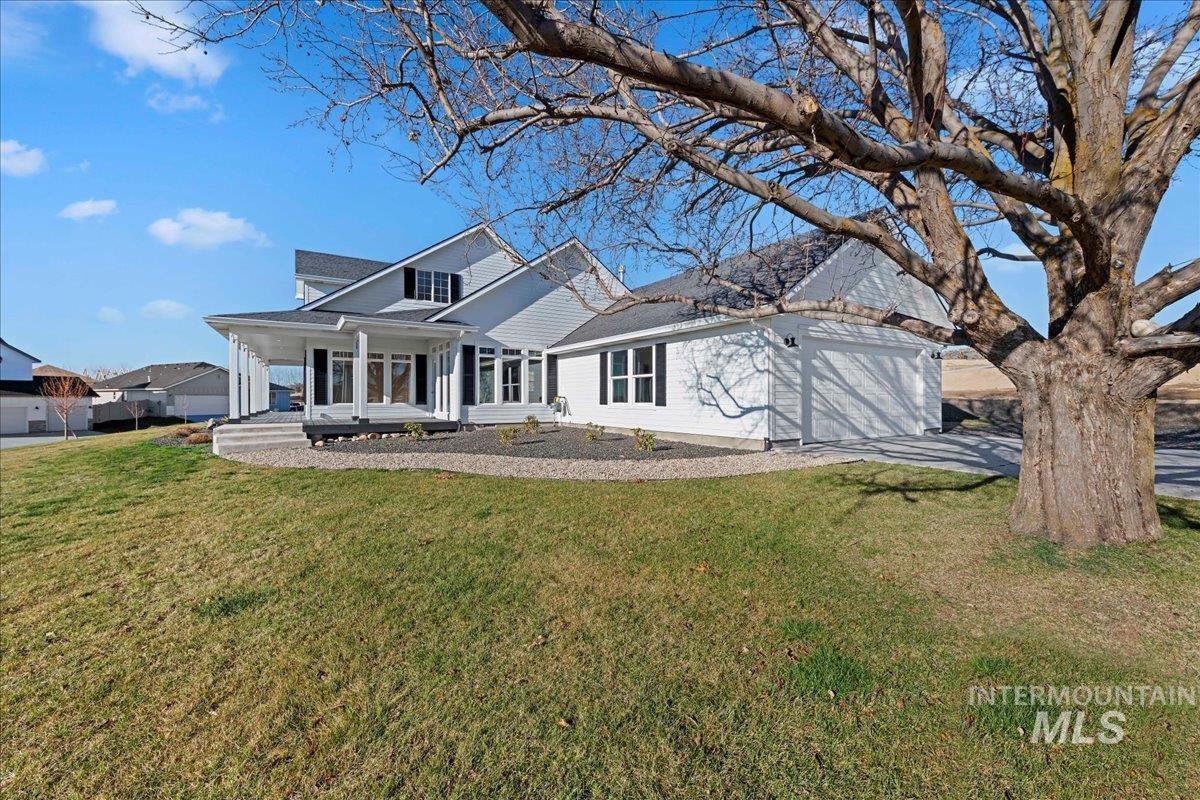 View of front of property with covered porch, a front yard, and an attached garage