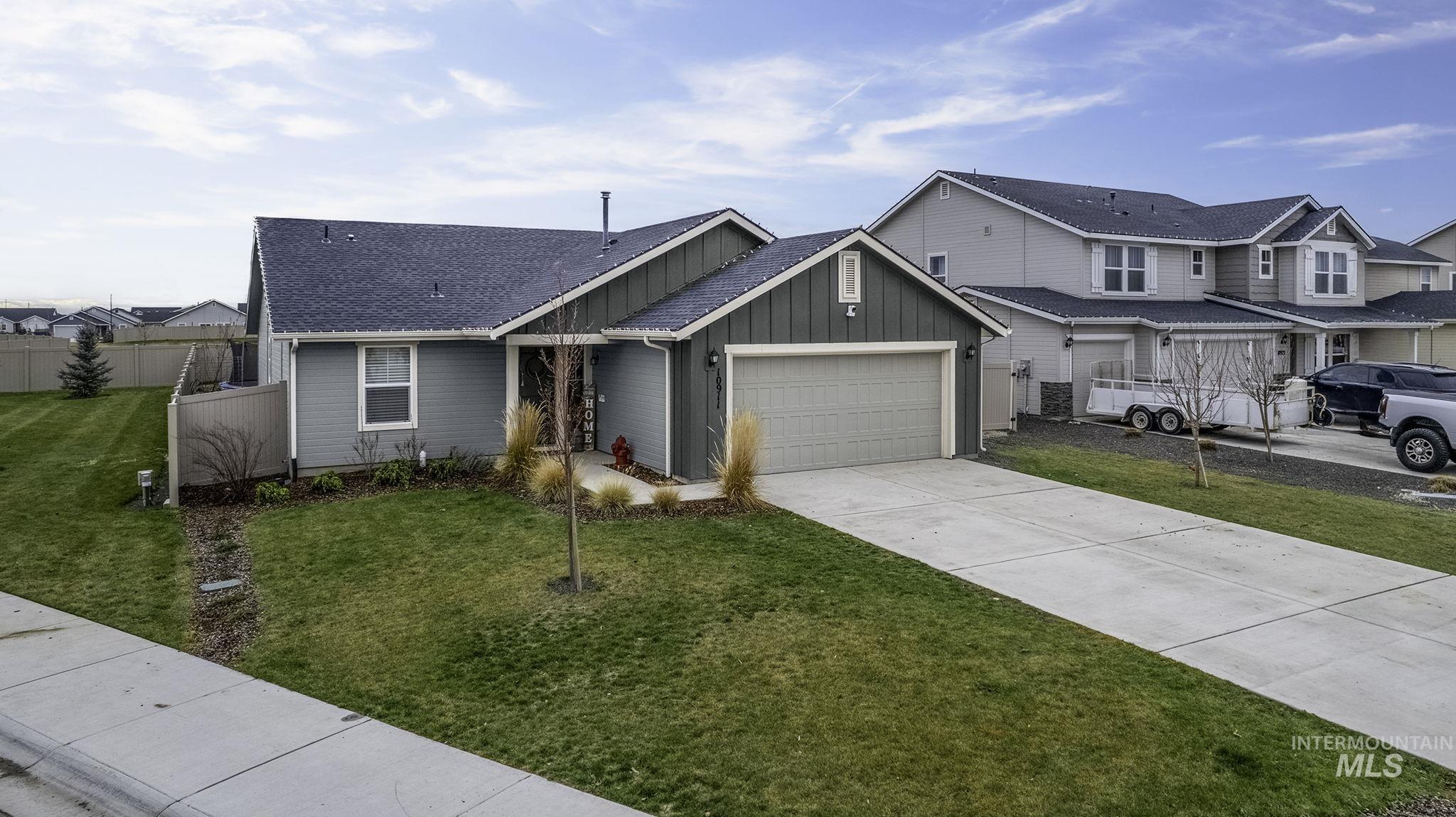View of front facade with board and batten siding, concrete driveway, an attached garage, roof with shingles, and a residential view