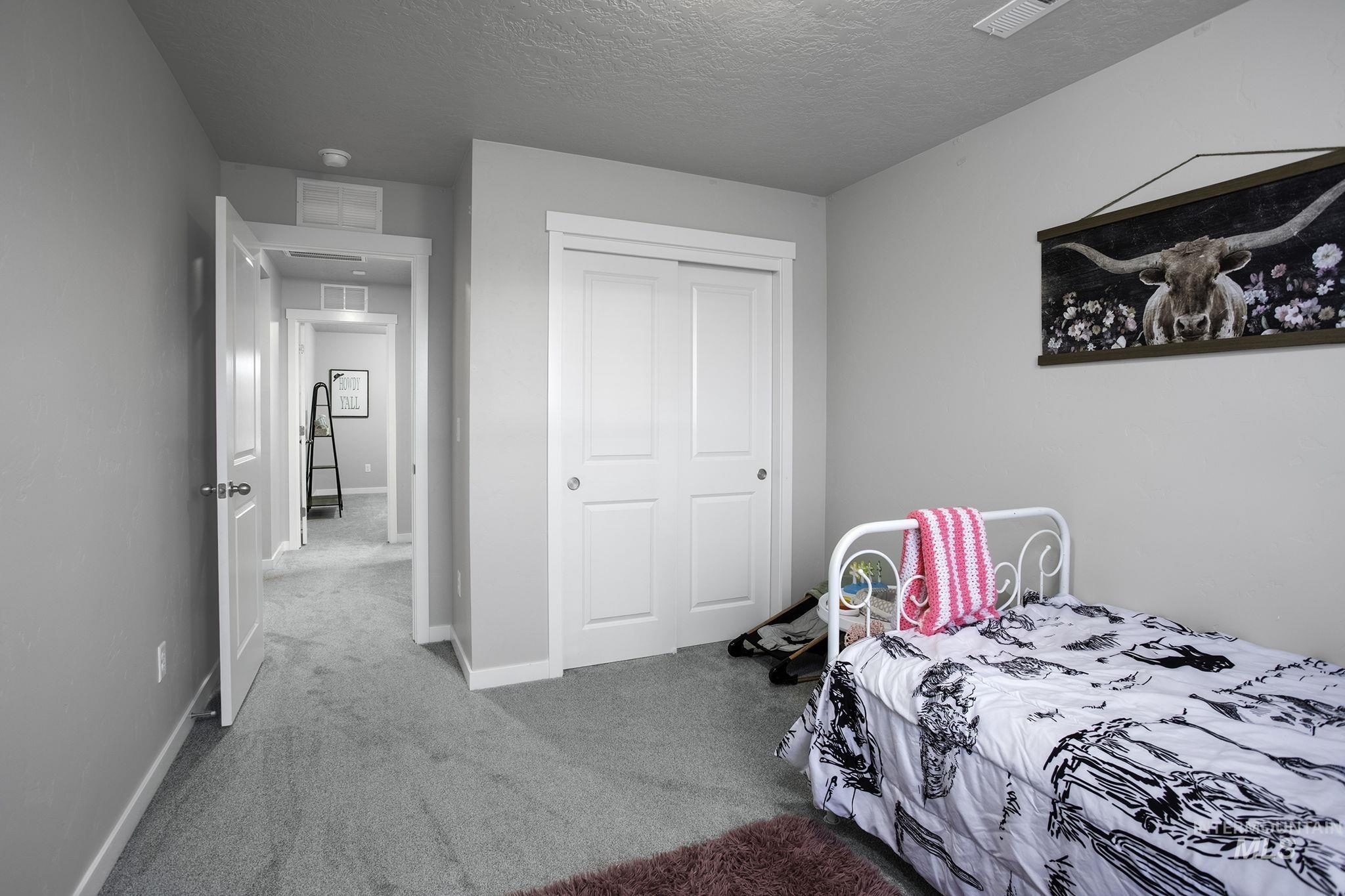 Bedroom featuring carpet flooring, a closet, and a textured ceiling