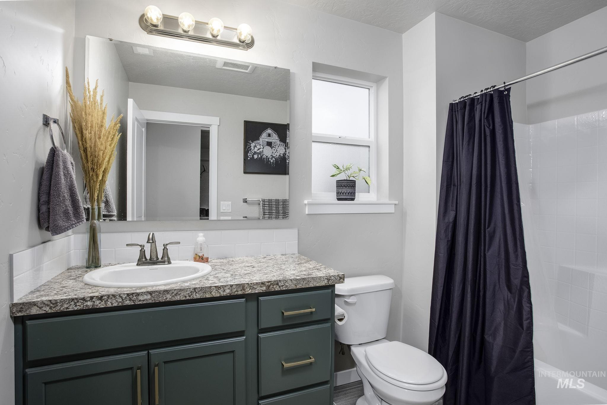 Full bath featuring vanity, shower / tub combo with curtain, and a textured ceiling
