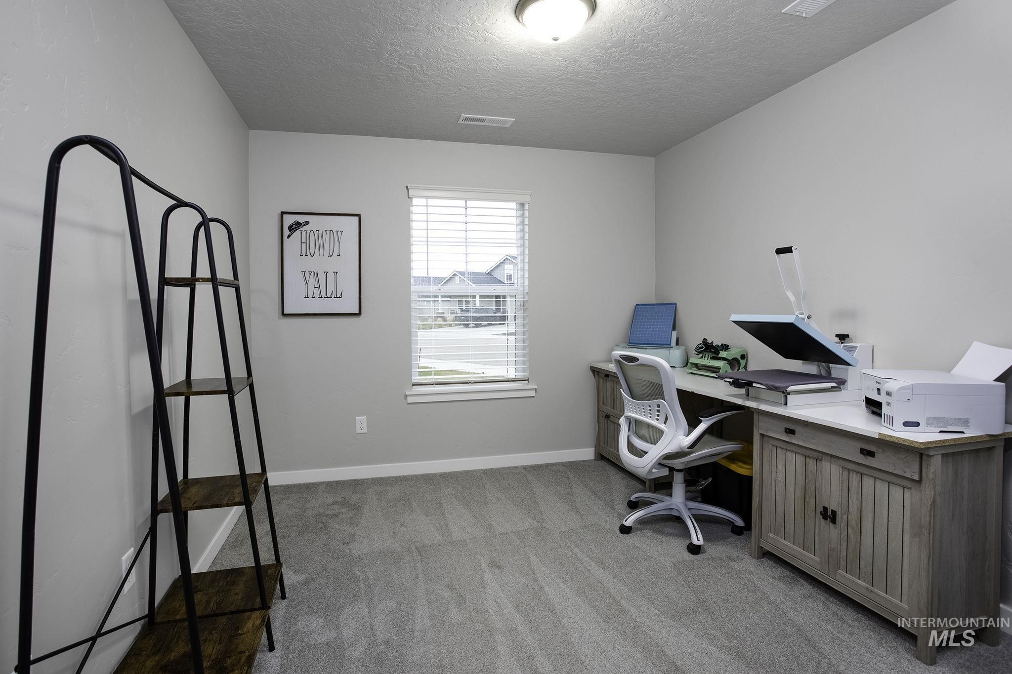 Home office featuring light carpet and a textured ceiling