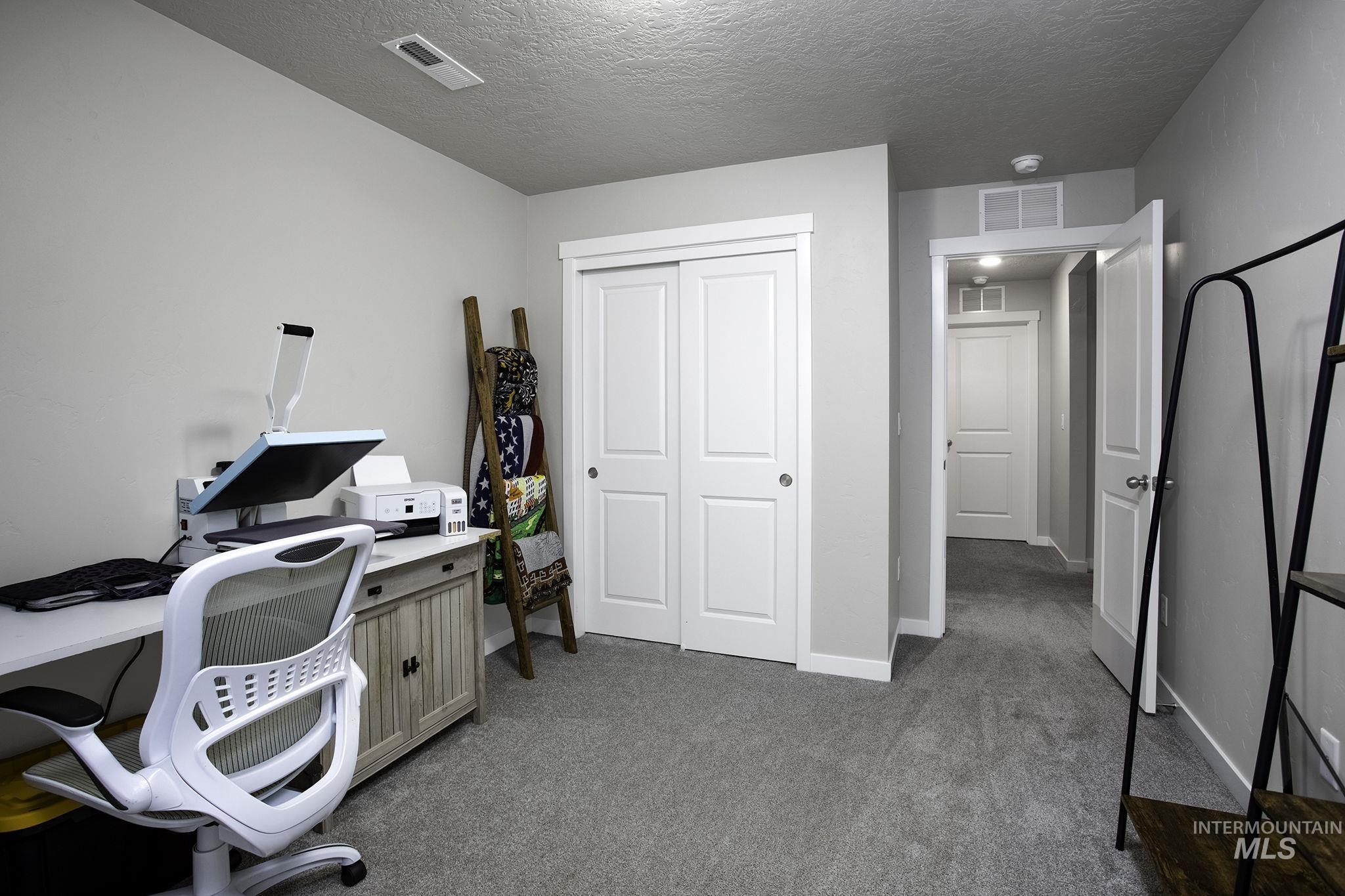 Office featuring dark colored carpet and a textured ceiling