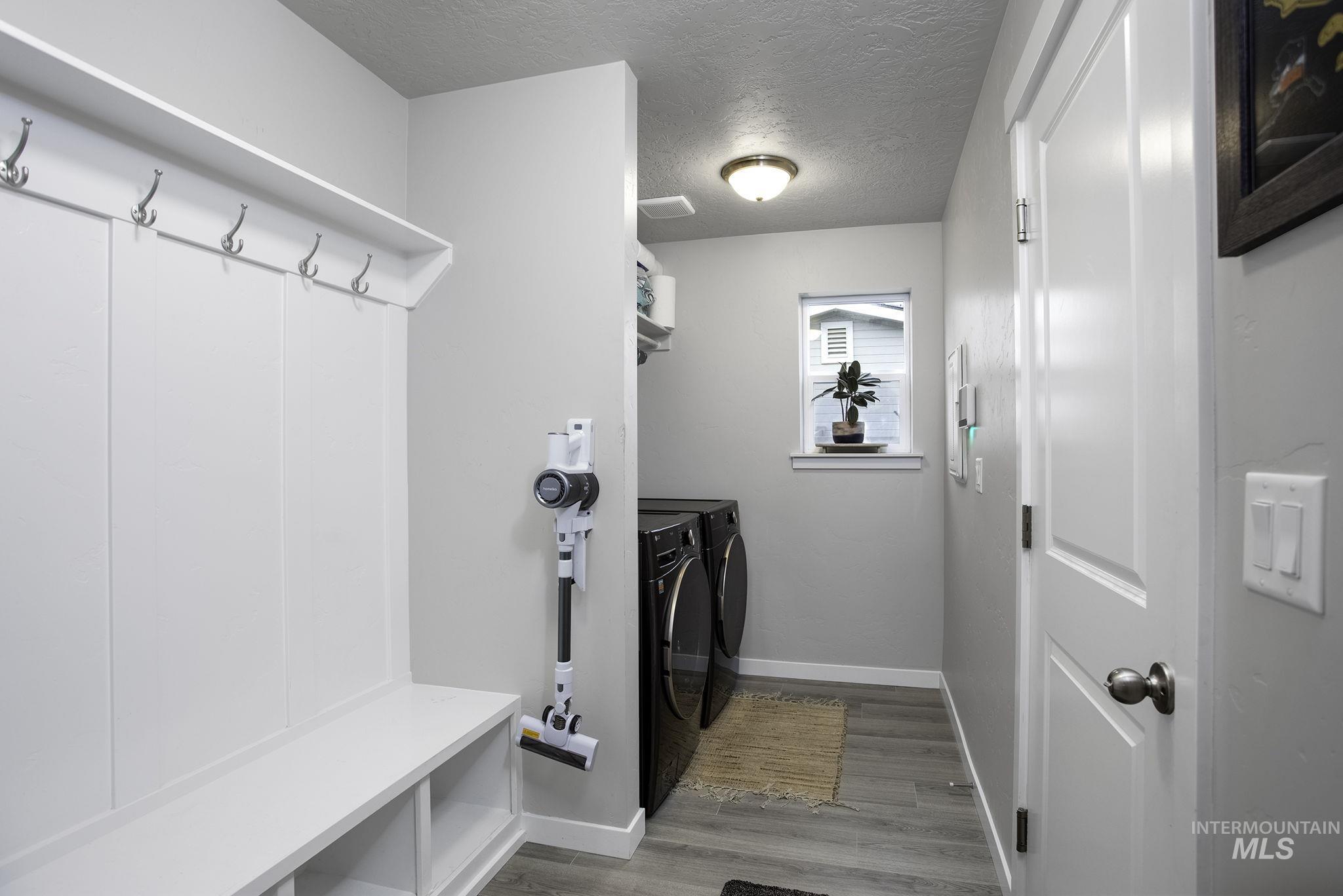 Mudroom with a textured ceiling, washing machine and dryer, and light wood-style floors