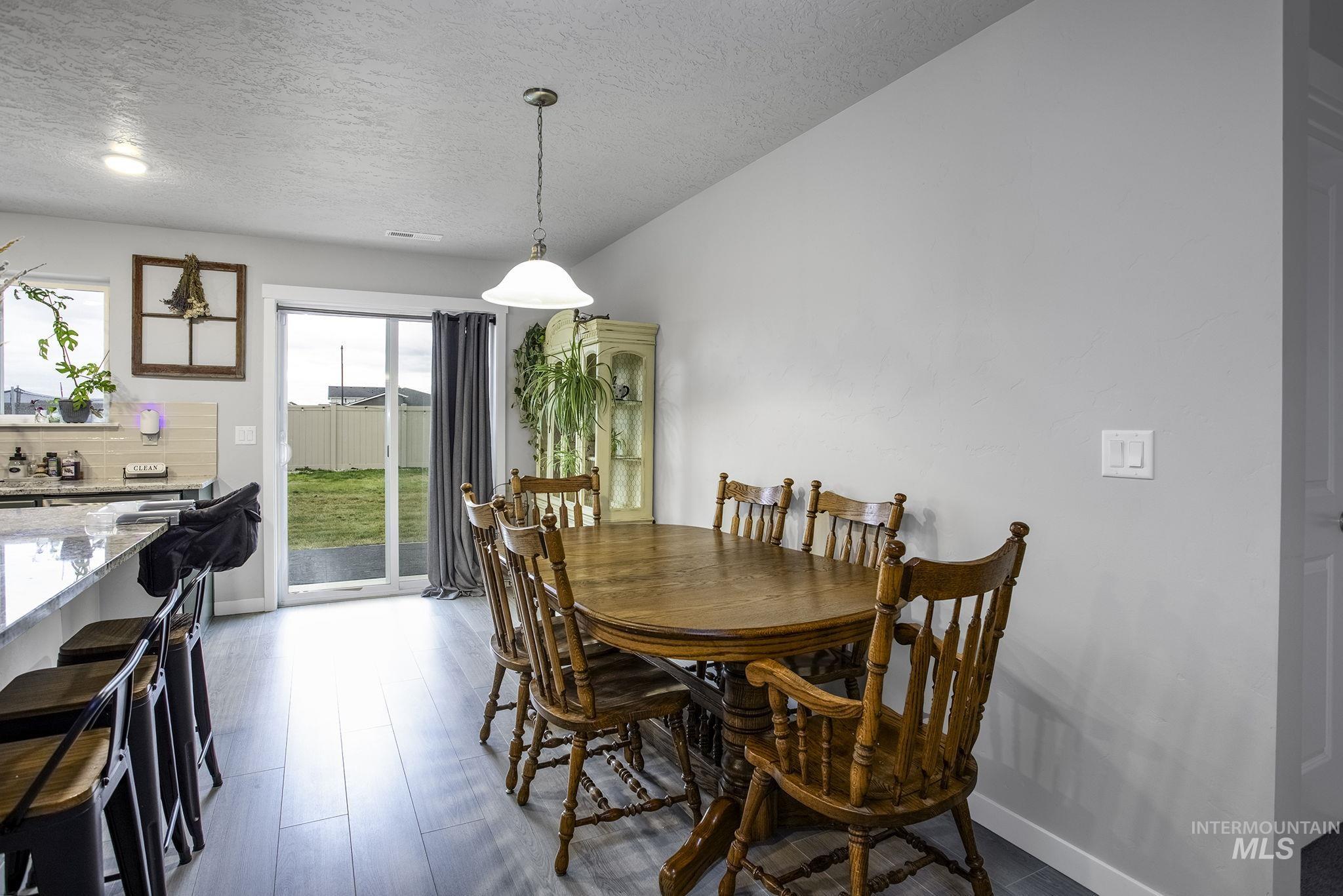 Dining area with a textured ceiling and dark wood-type flooring