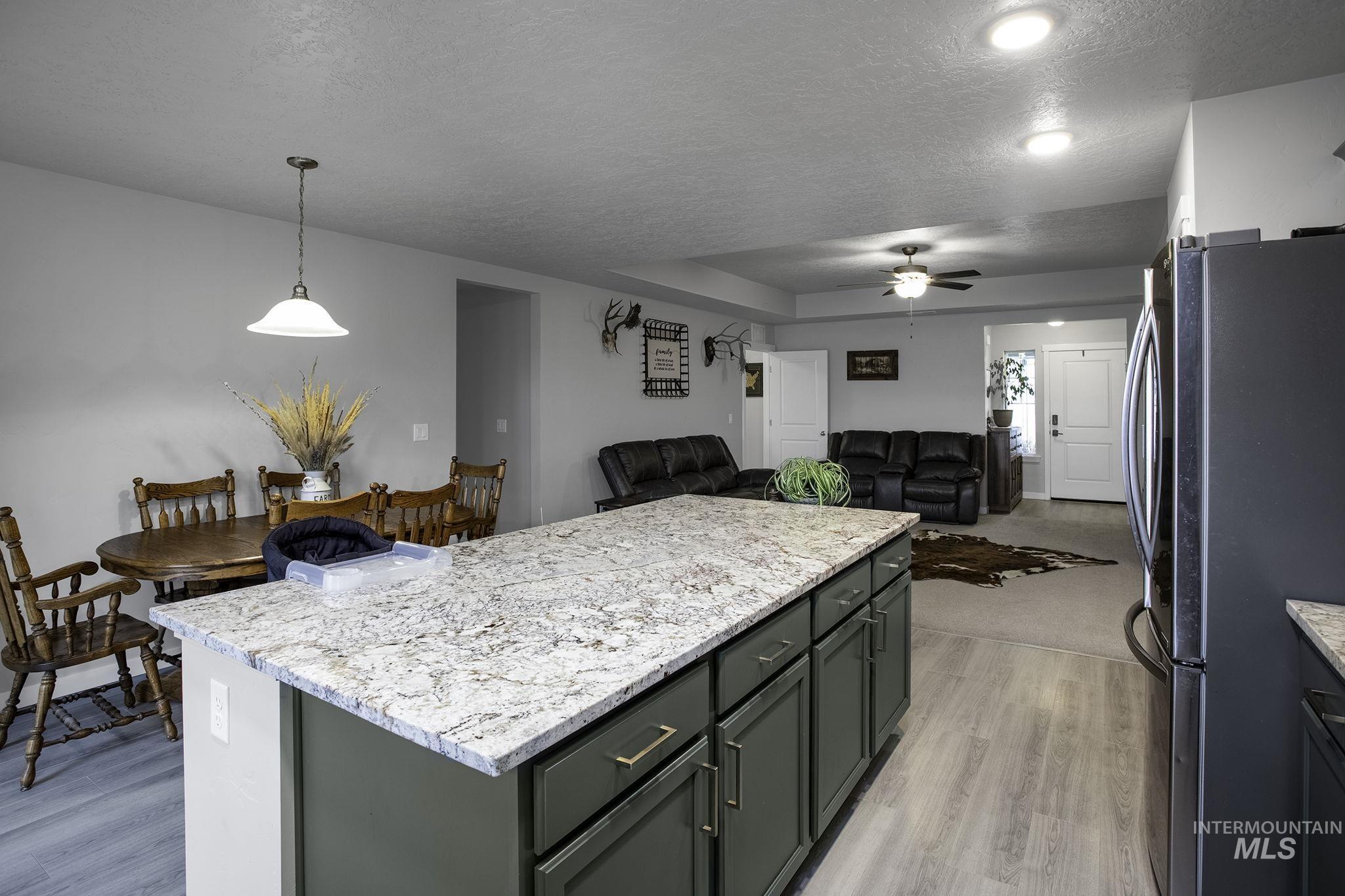 Kitchen featuring freestanding refrigerator, a center island, decorative light fixtures, a textured ceiling, and open floor plan