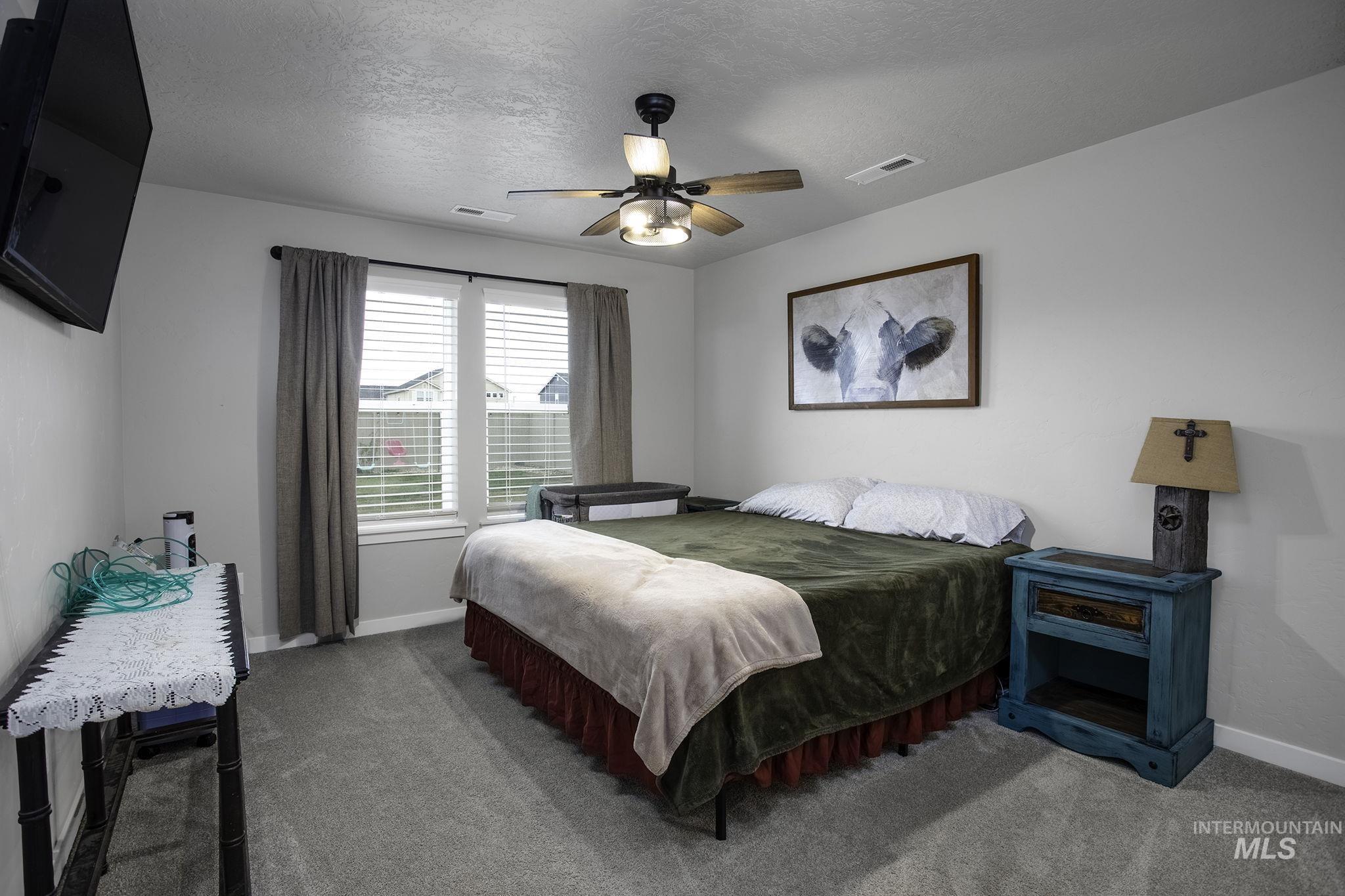 Carpeted bedroom with a textured ceiling and ceiling fan