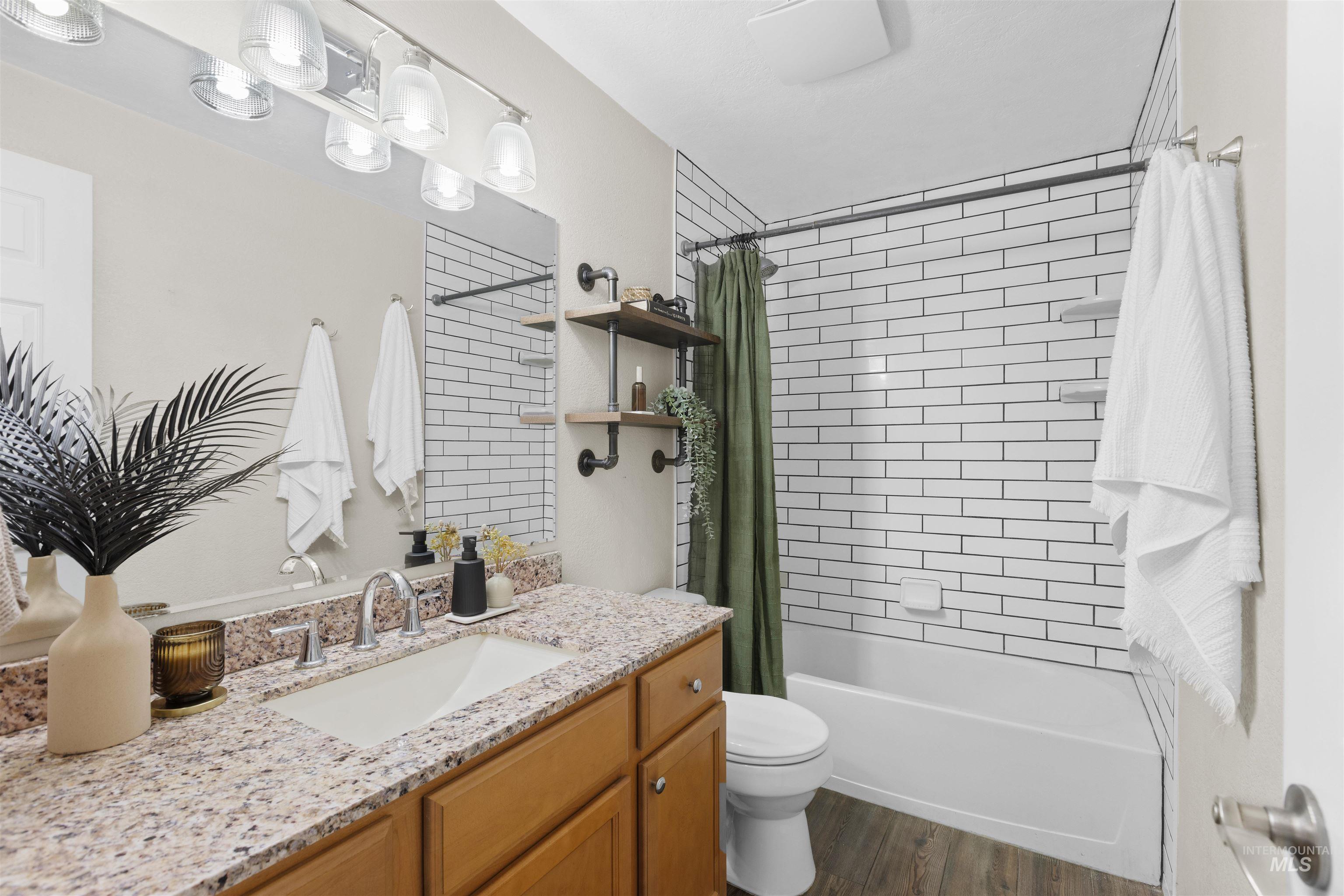Bathroom featuring shower / tub combo, vanity, and dark wood-style floors