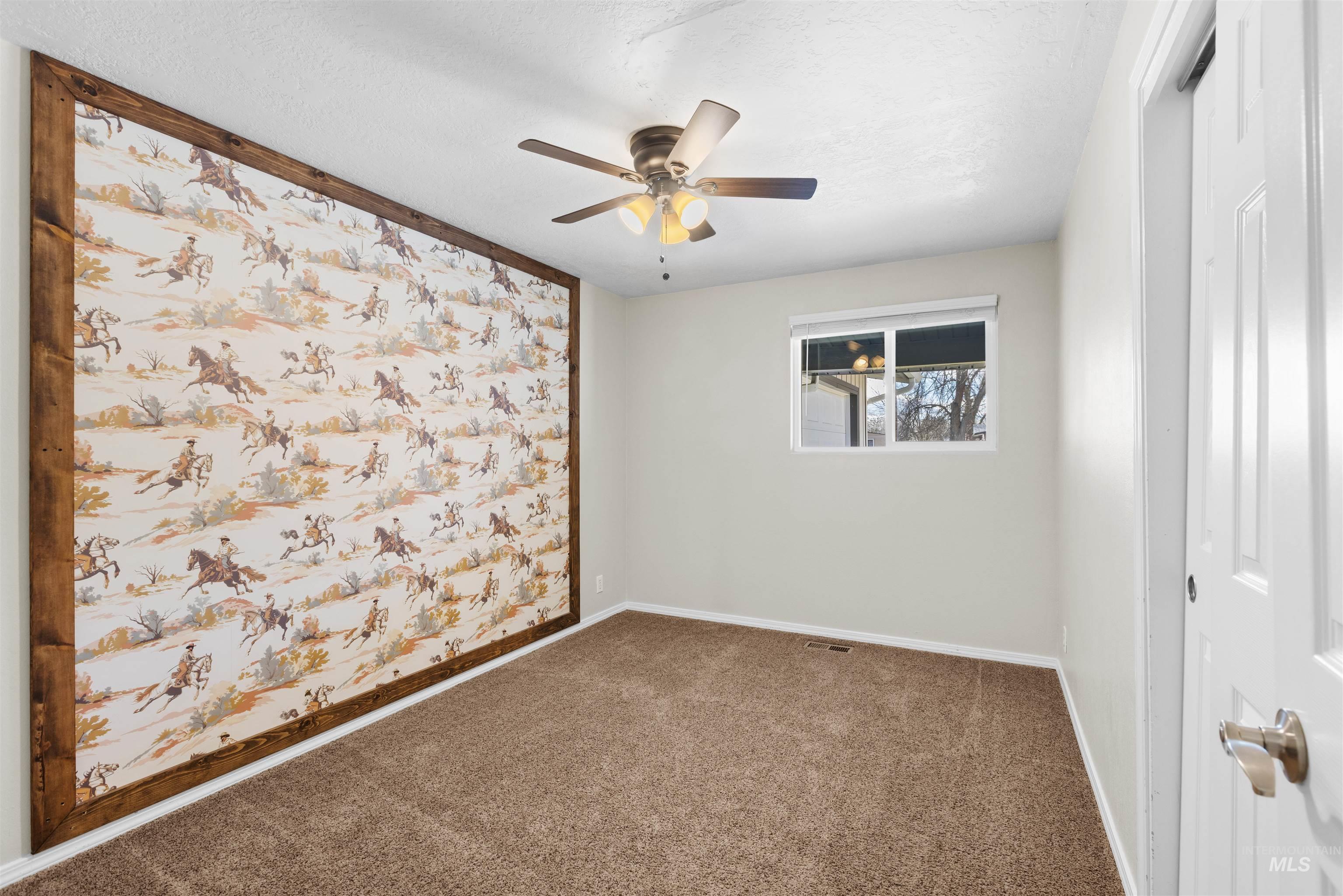 Spare room with carpet flooring, a ceiling fan, and a textured ceiling