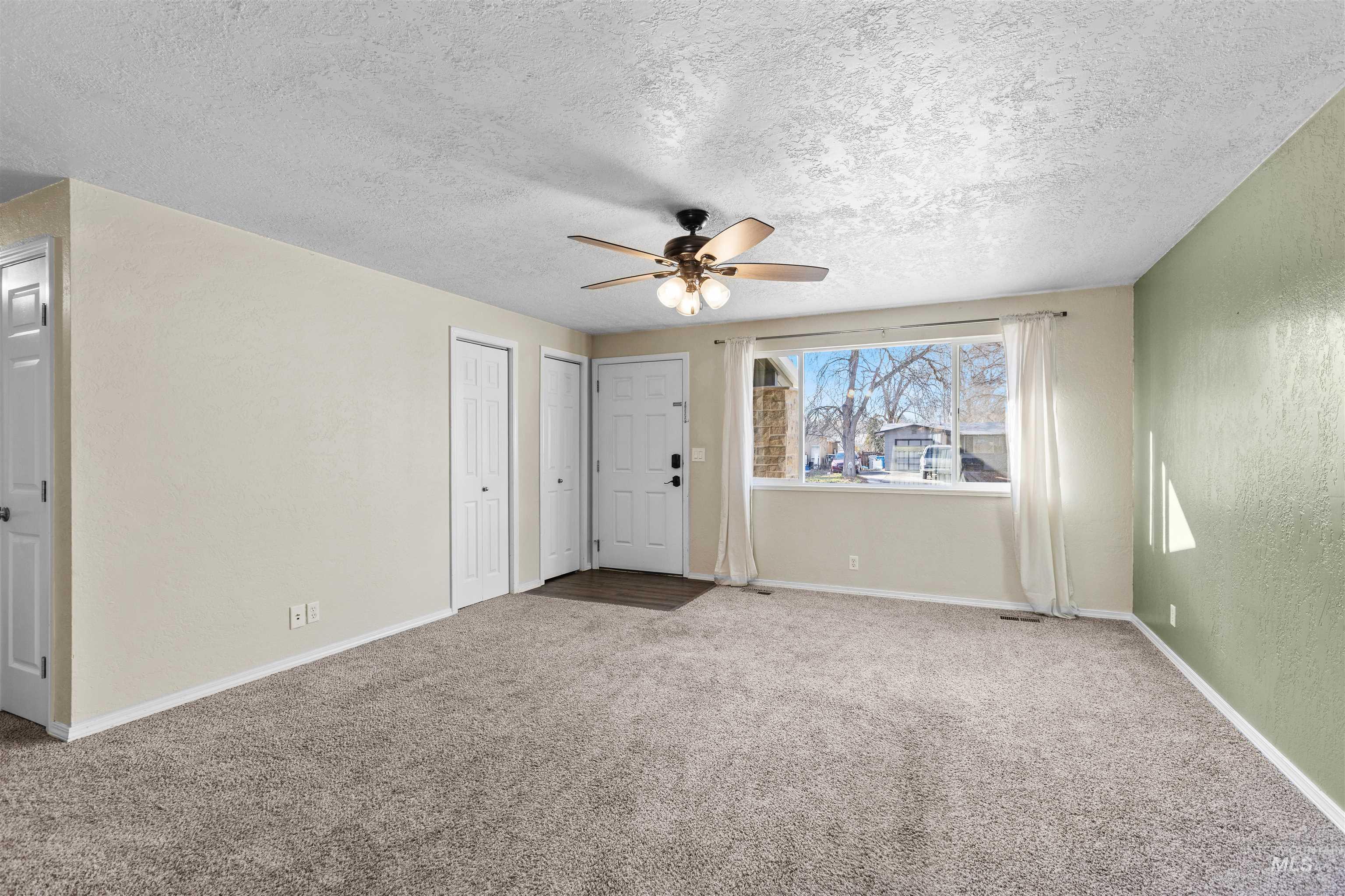 Unfurnished living room with a textured ceiling, carpet, a textured wall, and ceiling fan