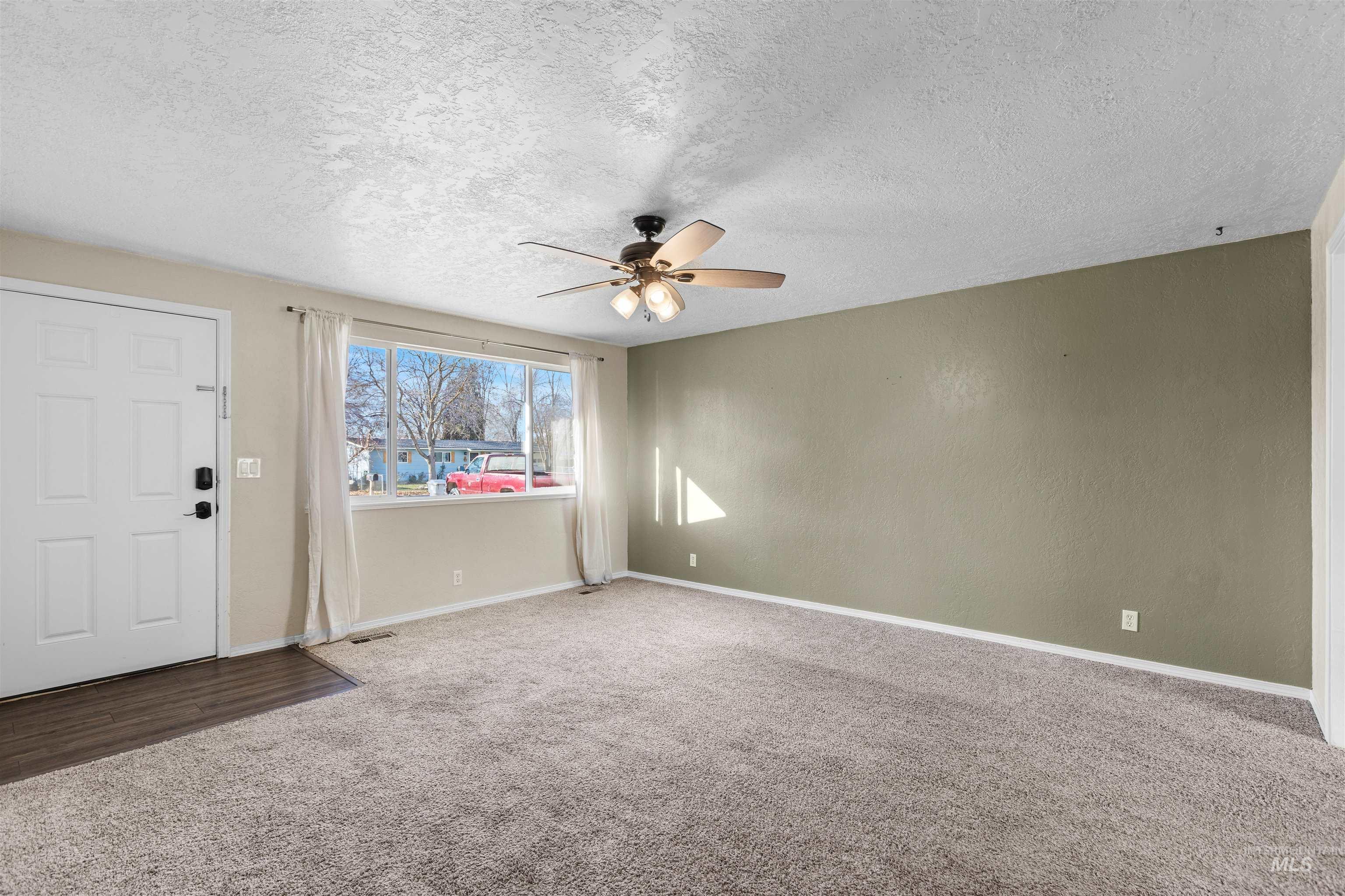 Entryway featuring a textured ceiling, carpet floors, and ceiling fan