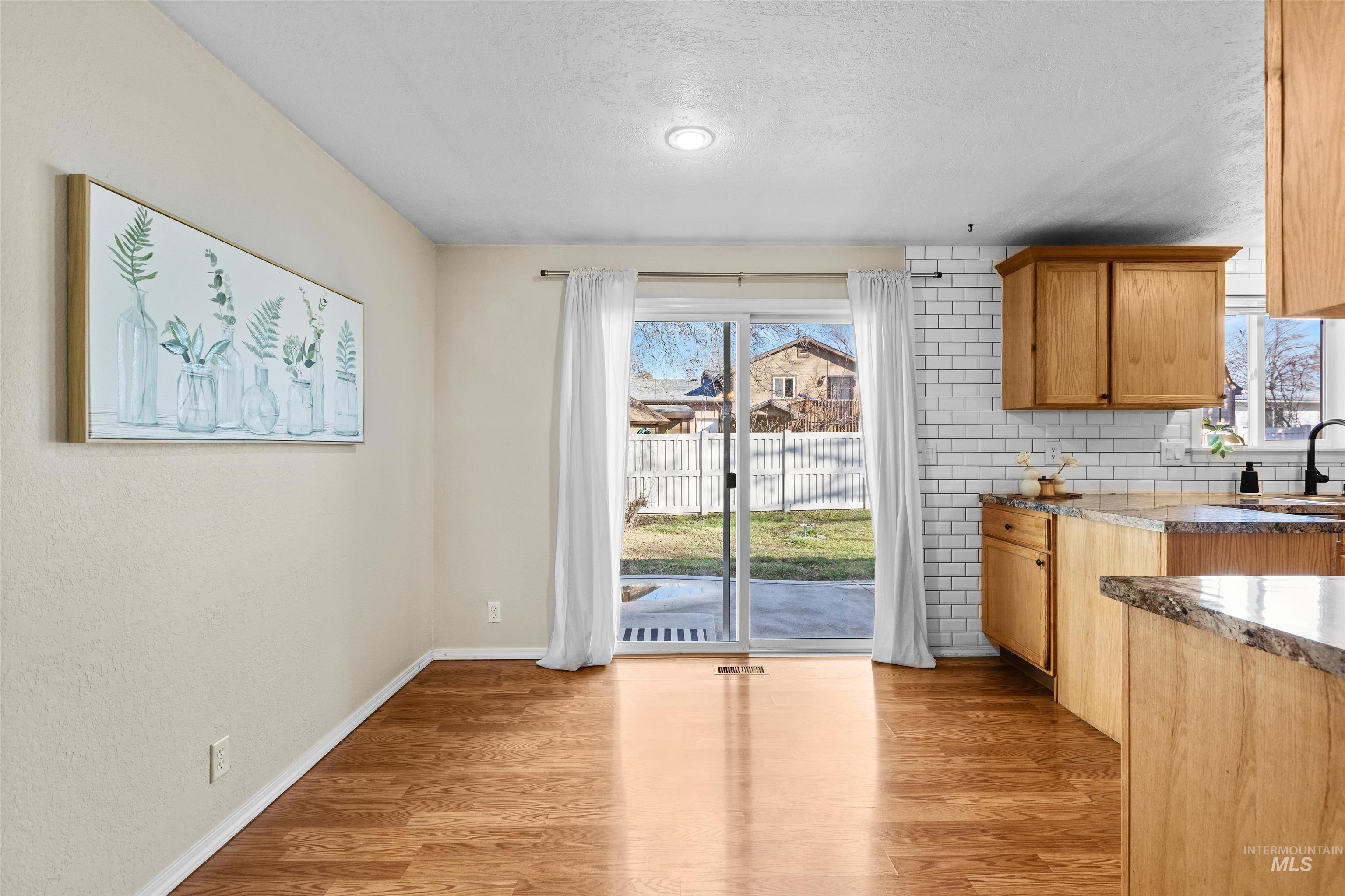Kitchen with light wood-style flooring, plenty of natural light, a textured ceiling, and backsplash
