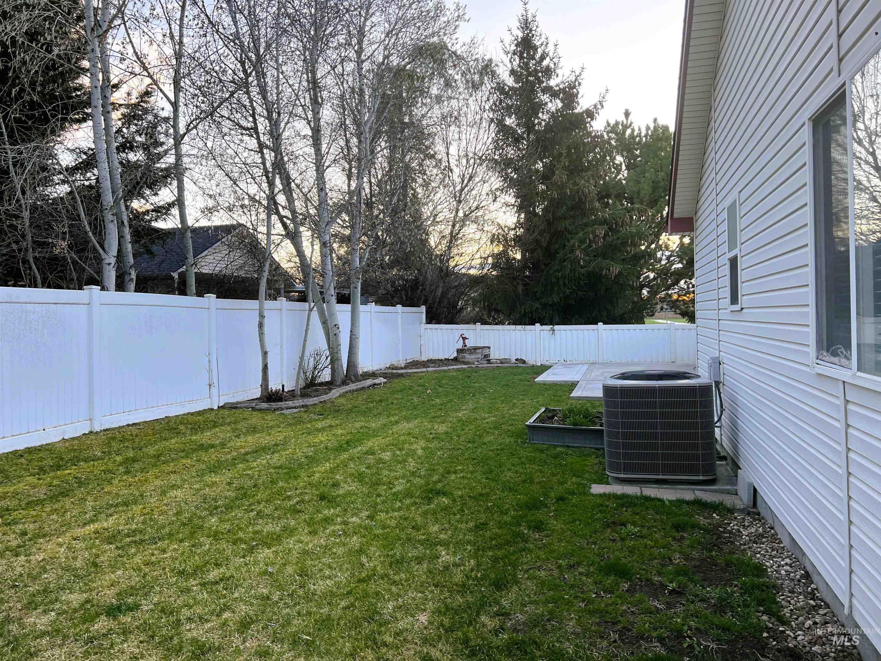 Fenced backyard with view of wooded area