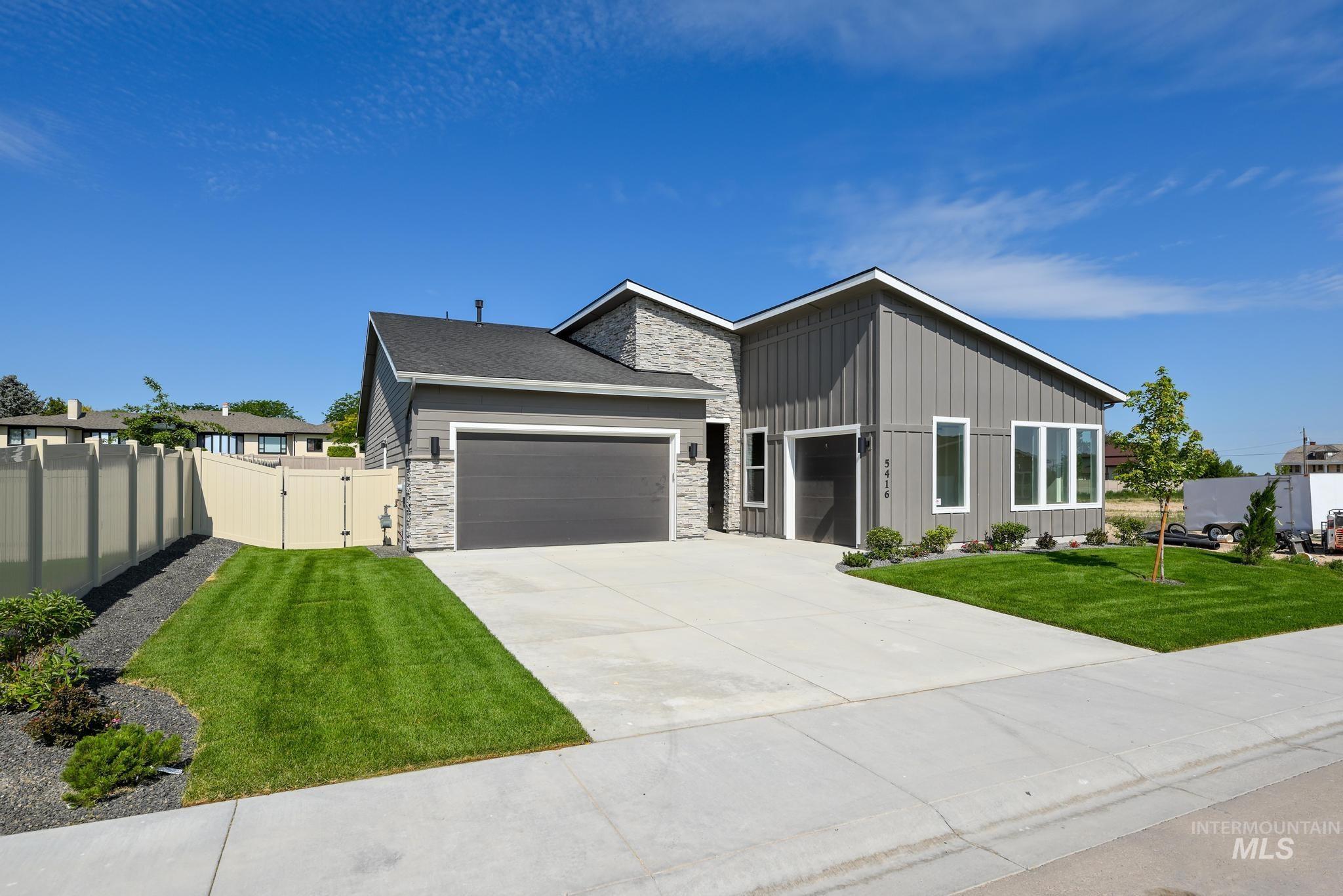 View of front facade featuring a gate, stone siding, an attached garage, board and batten siding, and concrete driveway