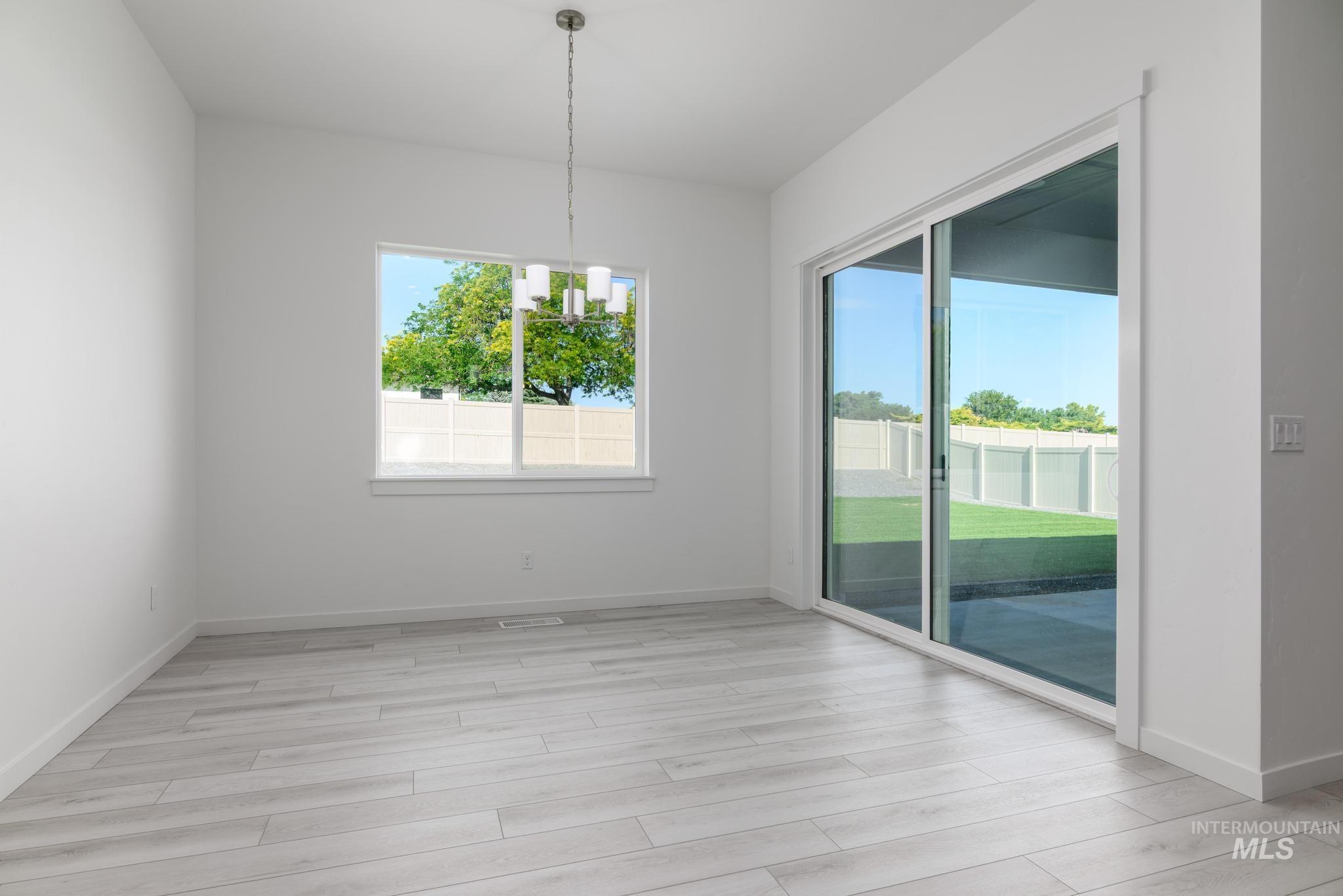 Unfurnished dining area featuring a chandelier and light wood-style floors