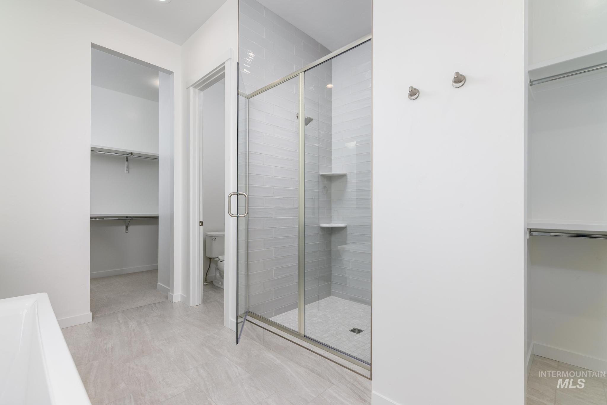 Bathroom with a shower stall and a walk in closet