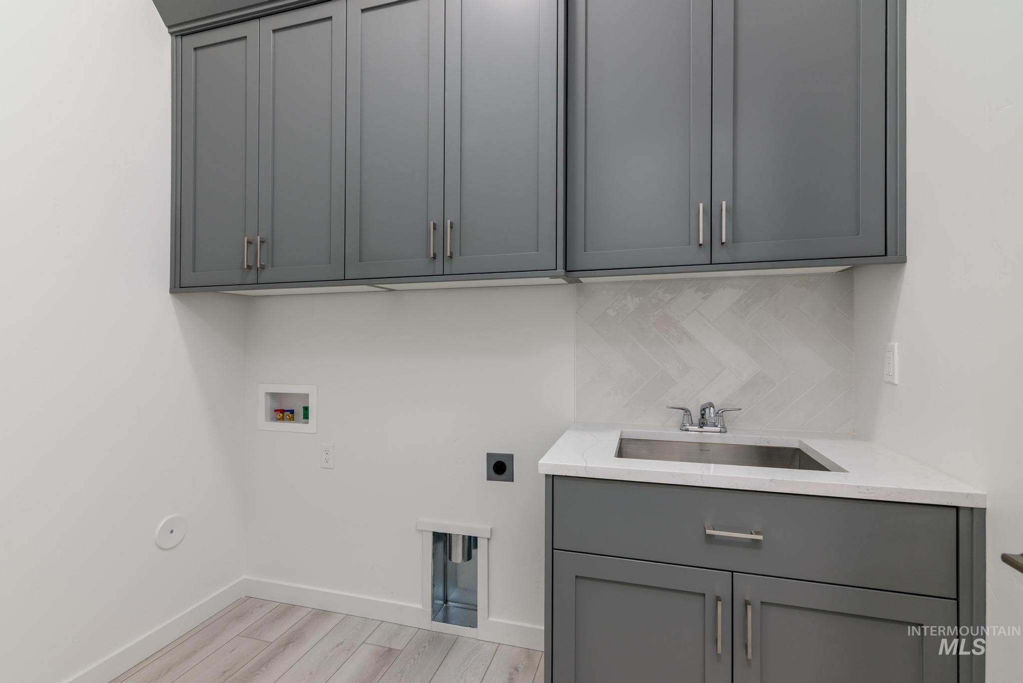 Laundry area with washer hookup, electric dryer hookup, light wood-style floors, and cabinet space