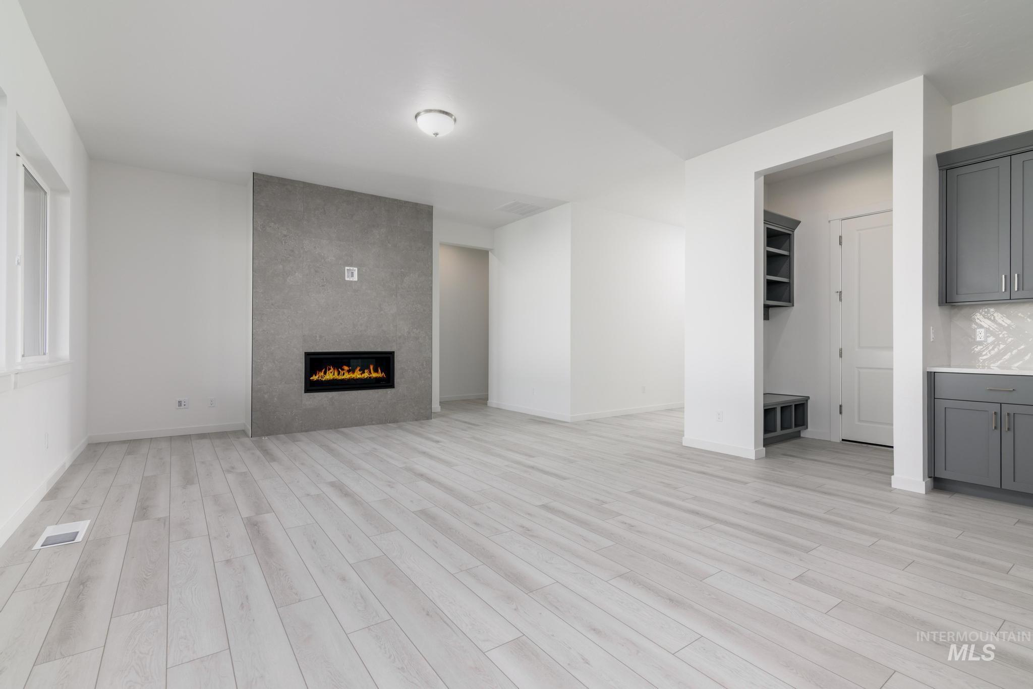 Unfurnished living room featuring light wood-style flooring and a tile fireplace