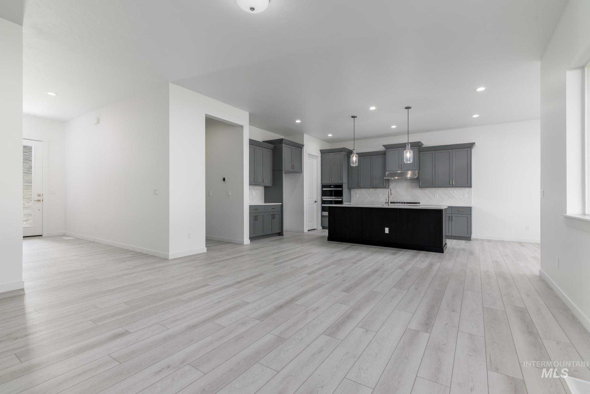 Kitchen with open floor plan, decorative backsplash, decorative light fixtures, an island with sink, and recessed lighting