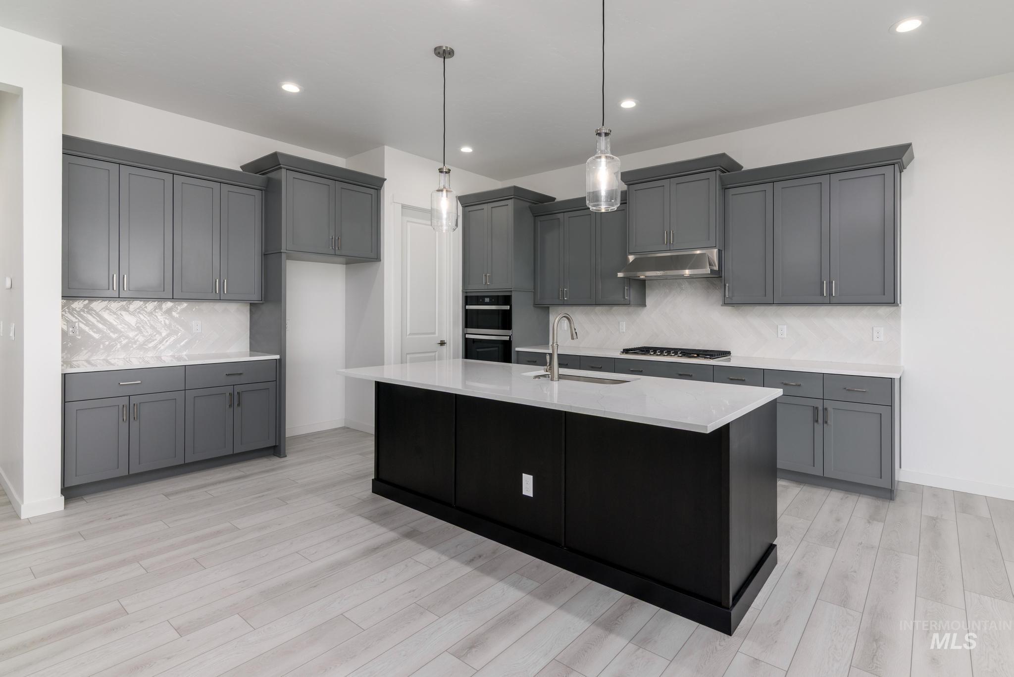 Kitchen with tasteful backsplash, hanging light fixtures, gray cabinetry, and recessed lighting
