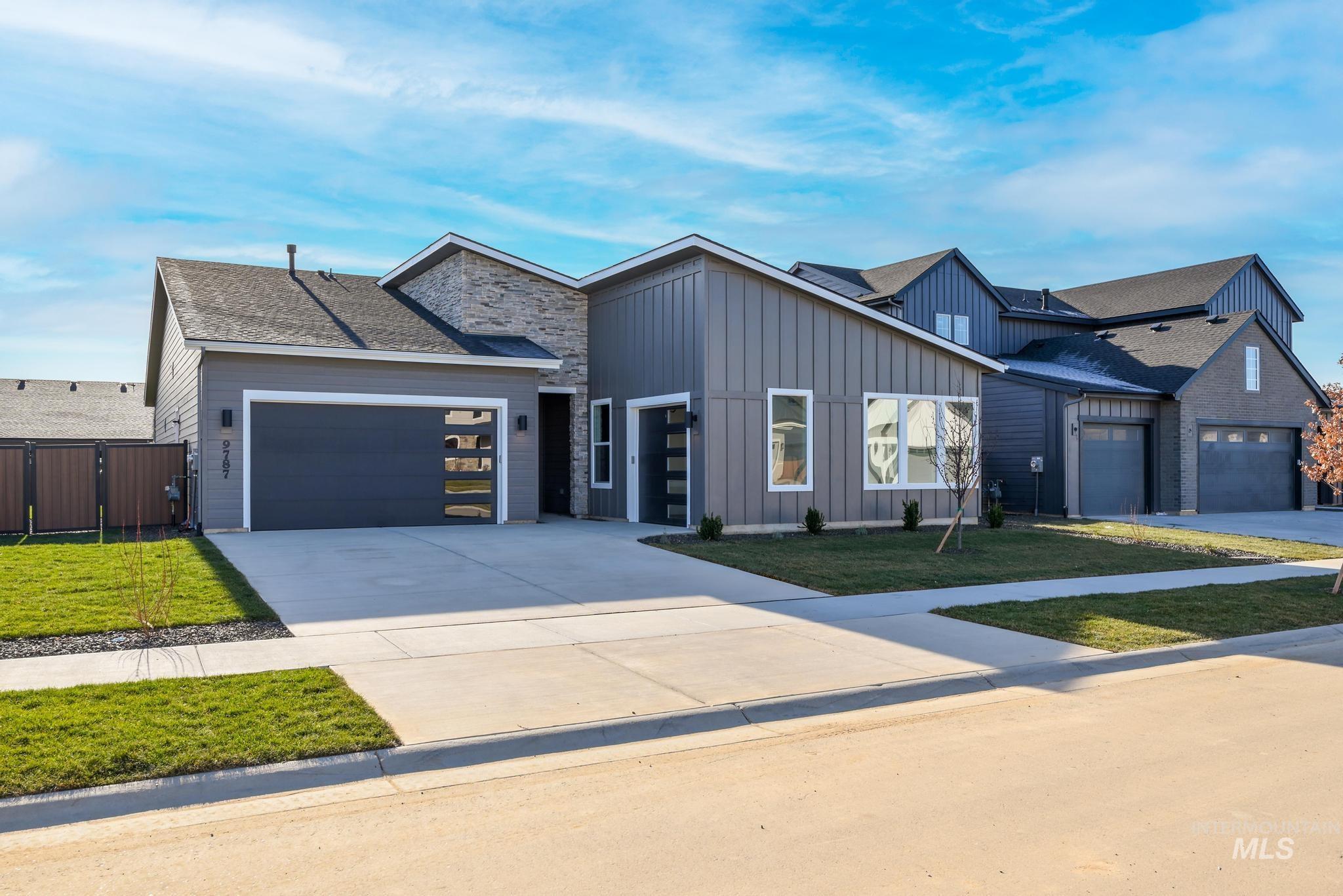 View of front of home featuring board and batten siding, concrete driveway, an attached garage, and a front lawn
