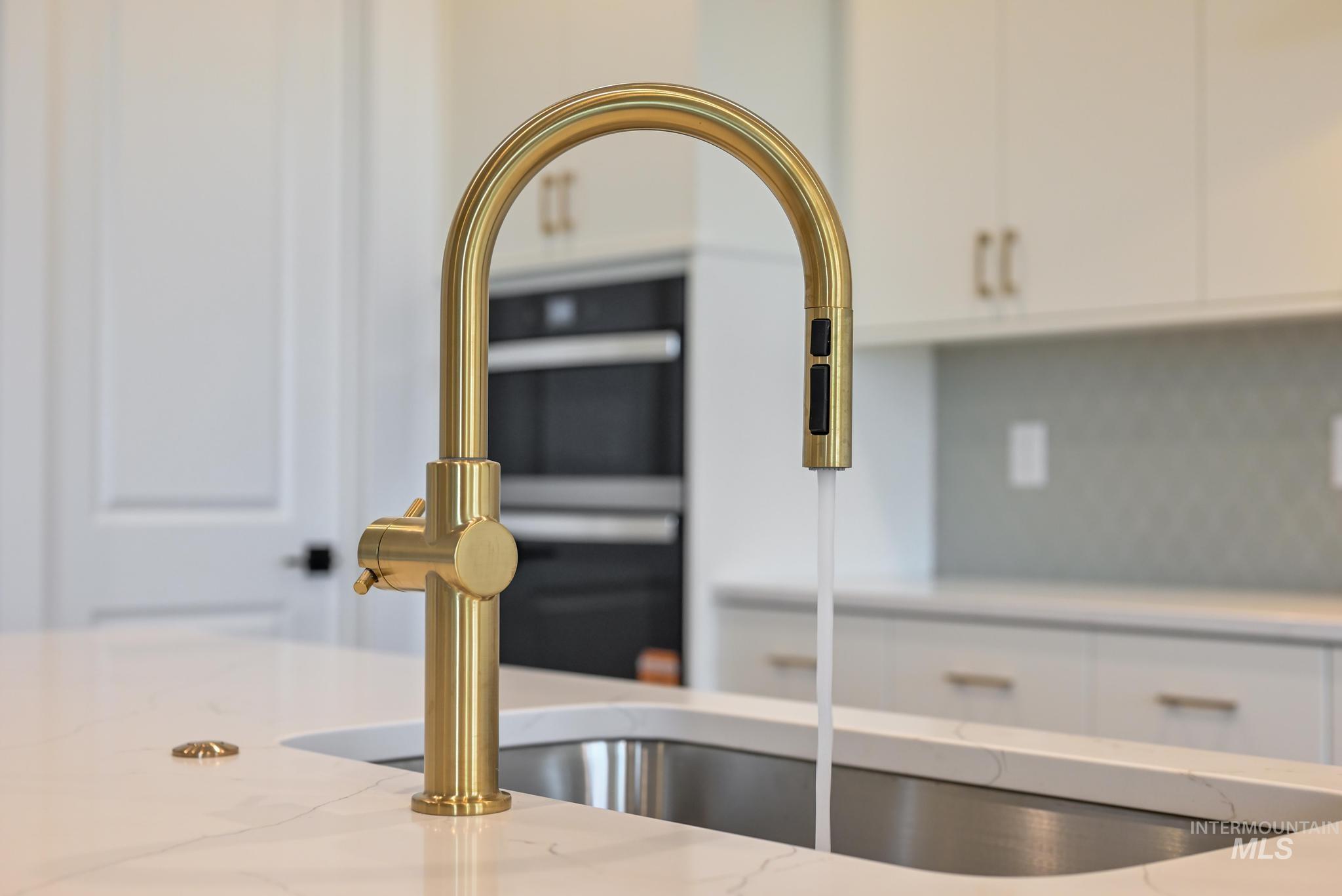 Kitchen view of white cabinets, light stone counters, and backsplash