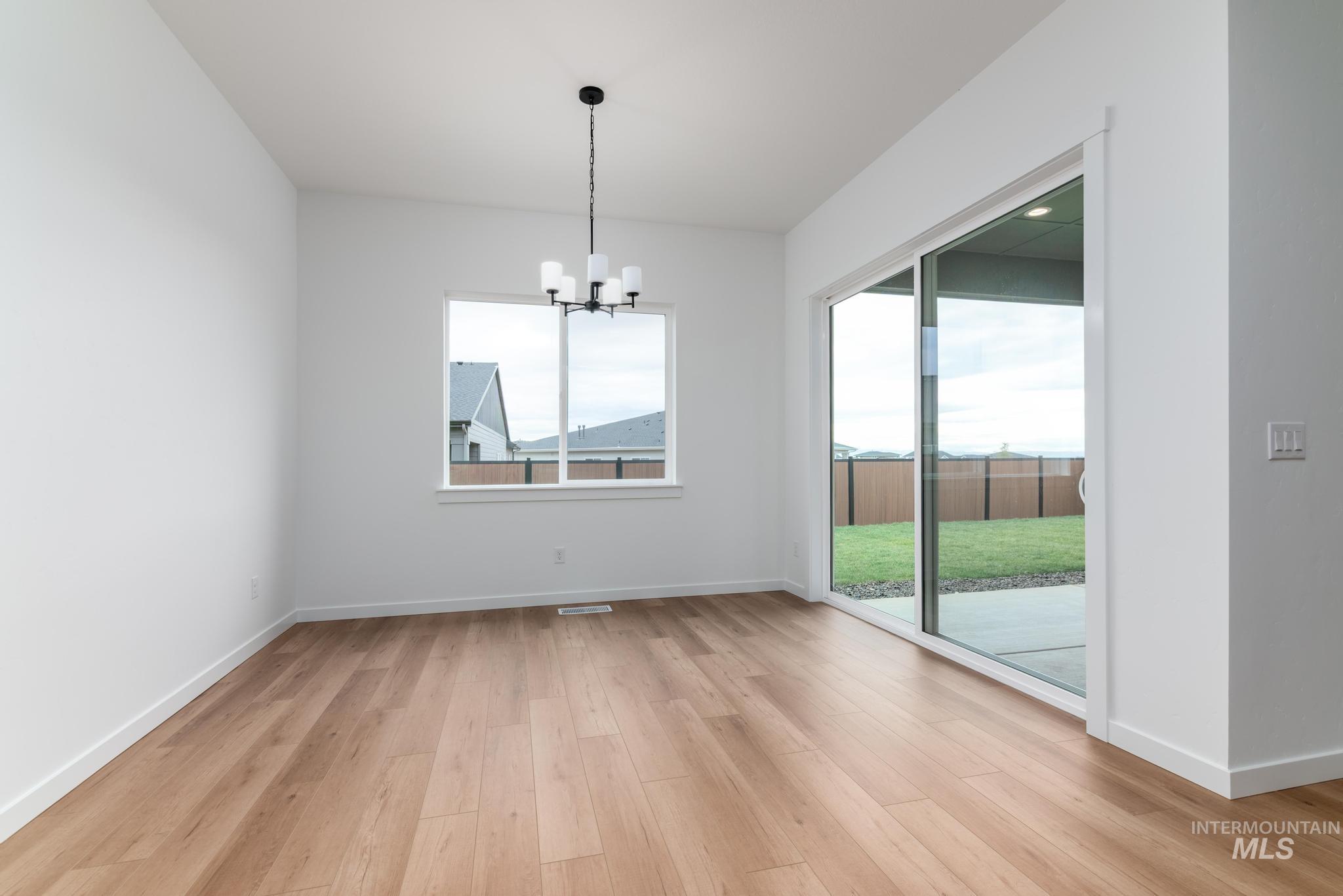 Unfurnished dining area with a chandelier and light wood-style floors