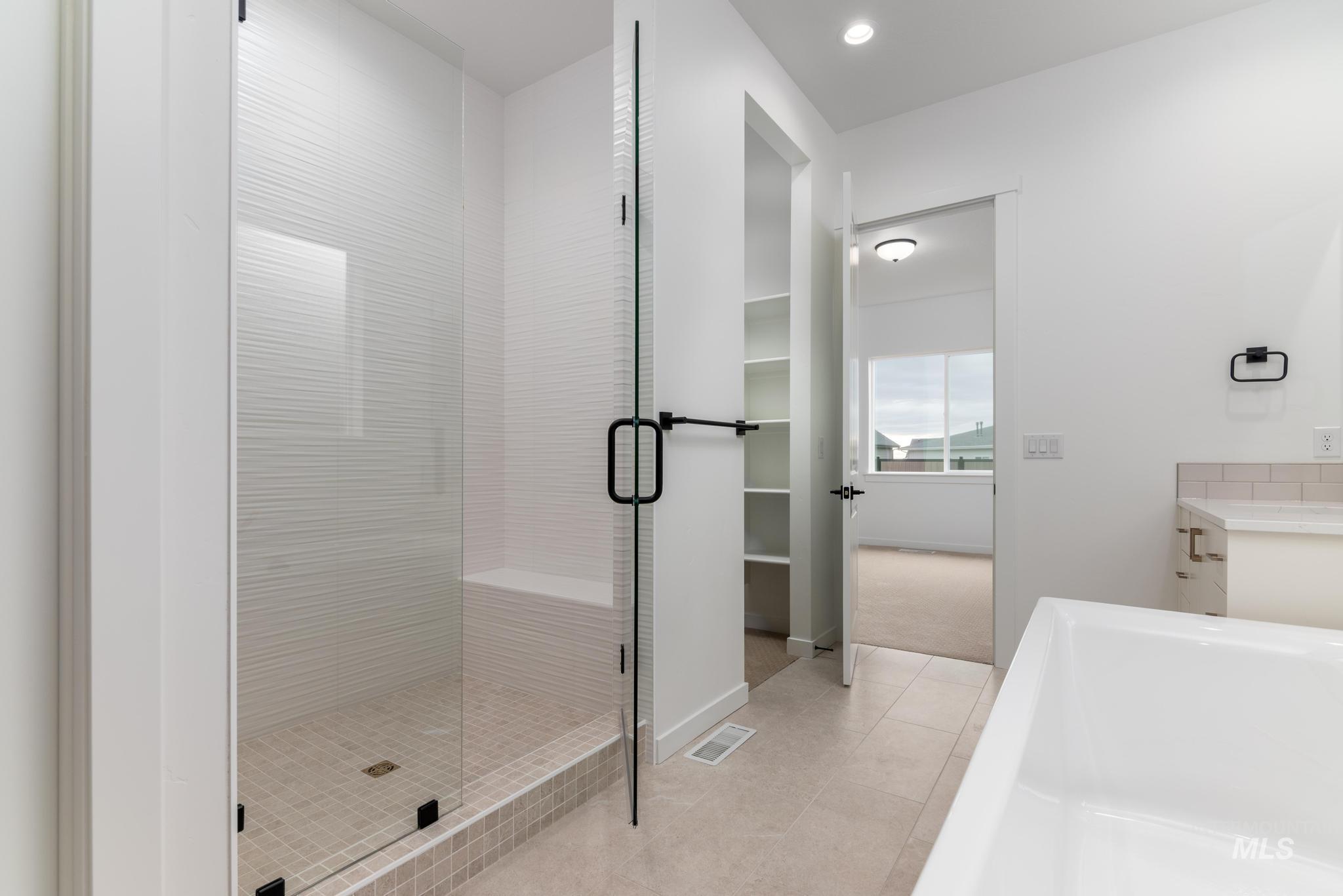 Full bath with vanity, a shower stall, light tile patterned flooring, a walk in closet, and recessed lighting