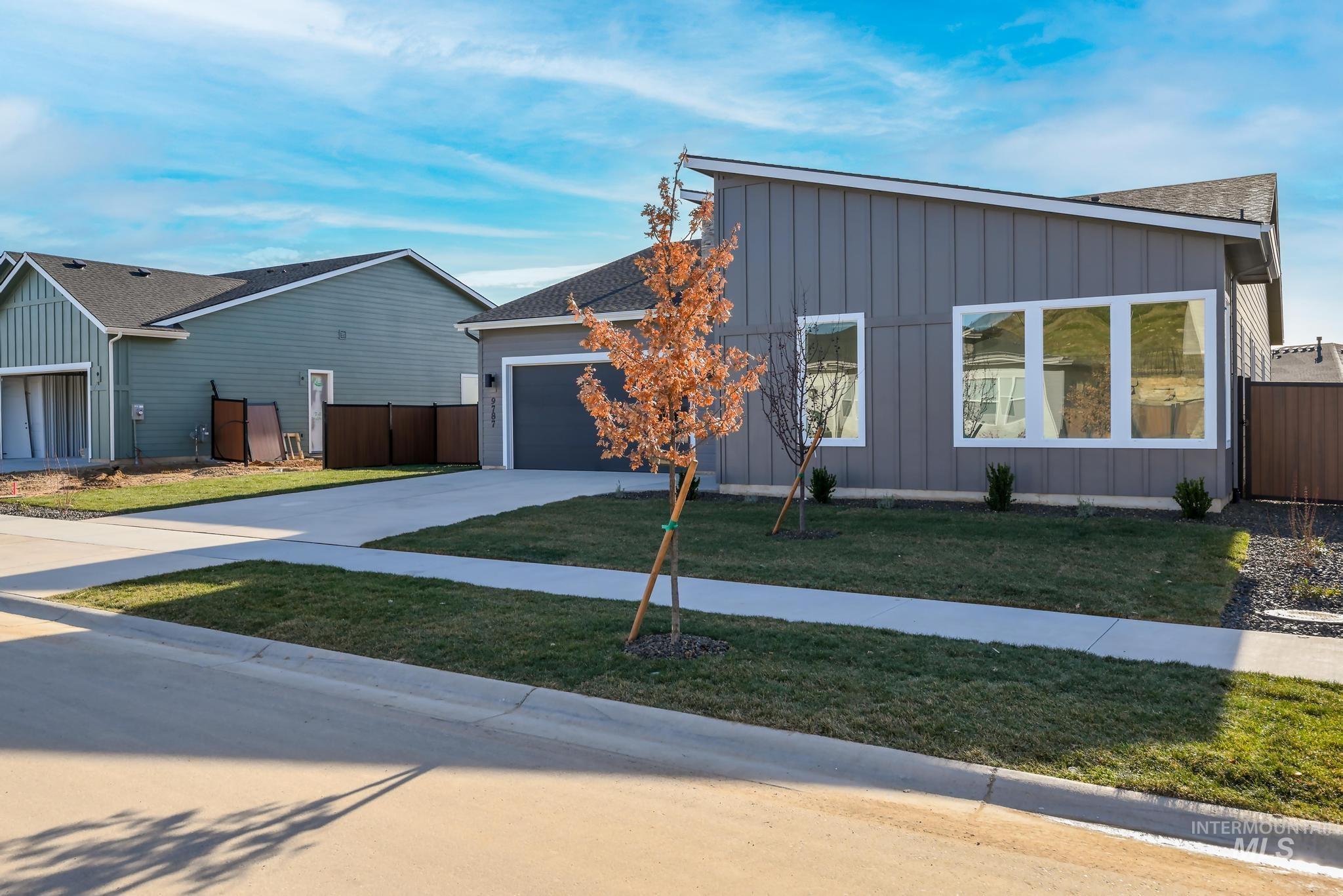 Contemporary house featuring board and batten siding, concrete driveway, roof with shingles, and an attached garage