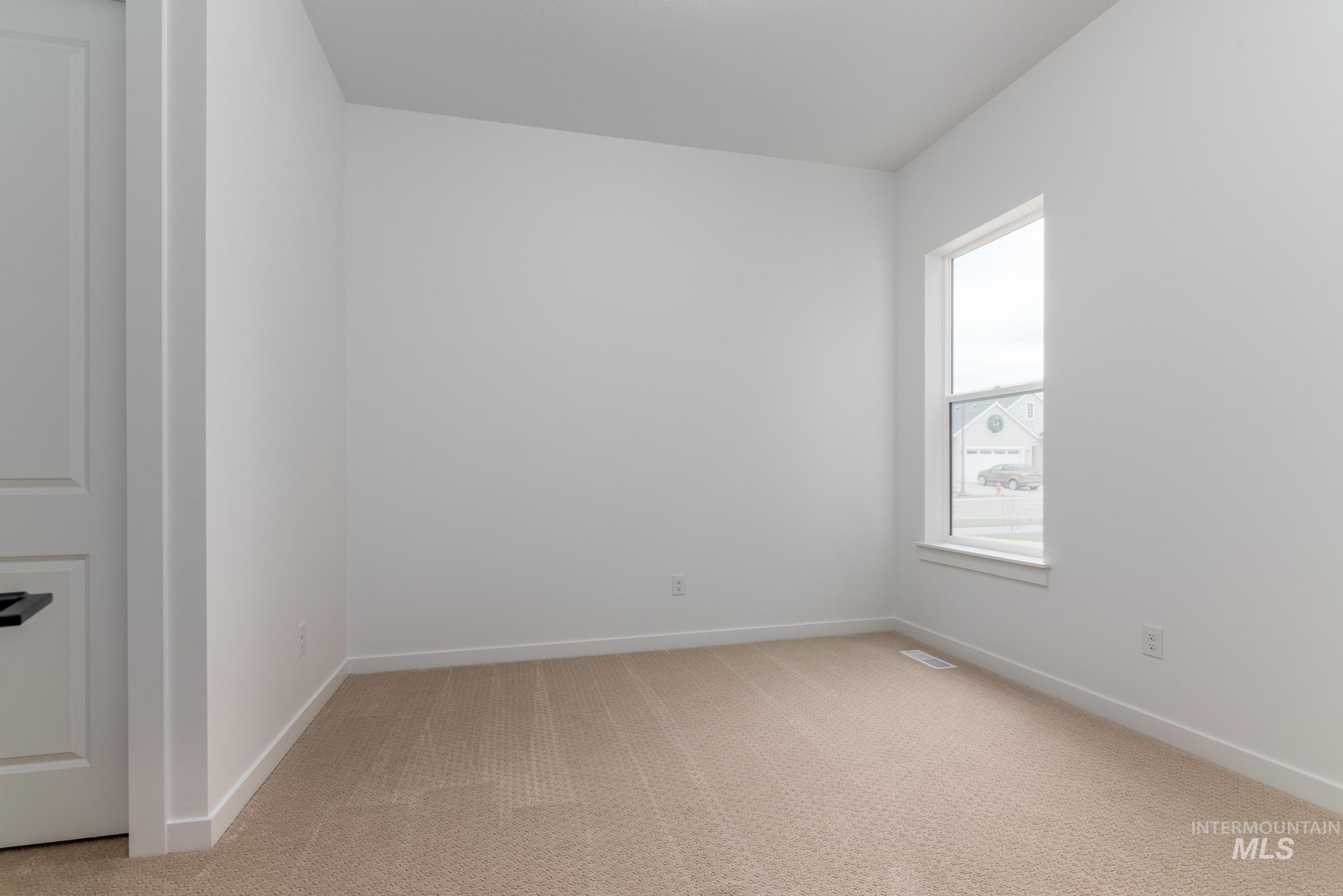 Empty room featuring light carpet and baseboards