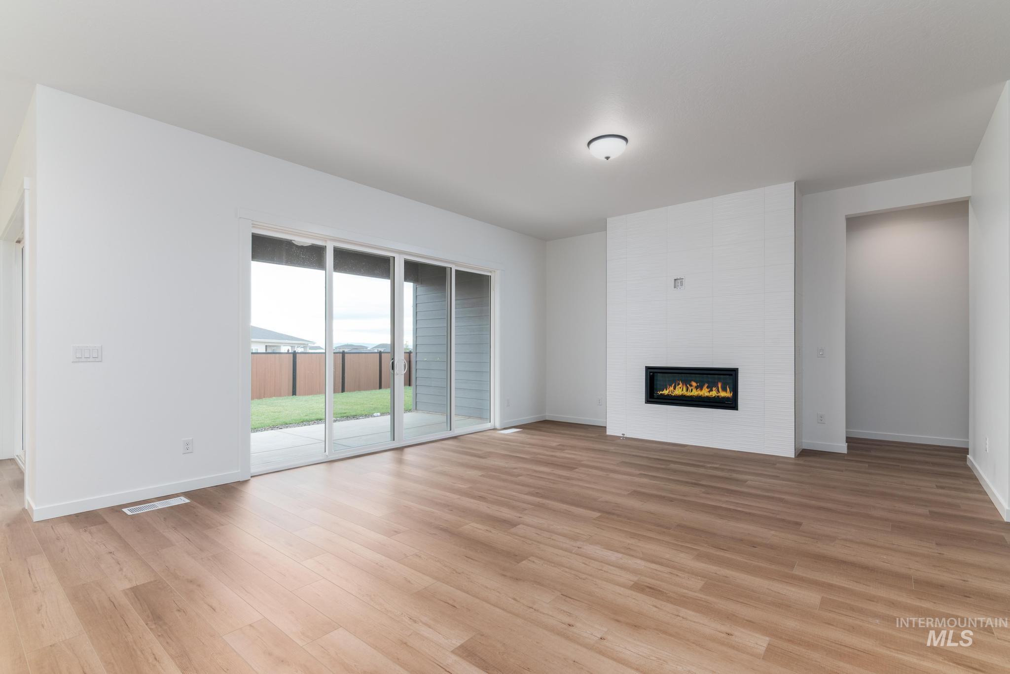 Unfurnished living room with a large fireplace and light wood finished floors