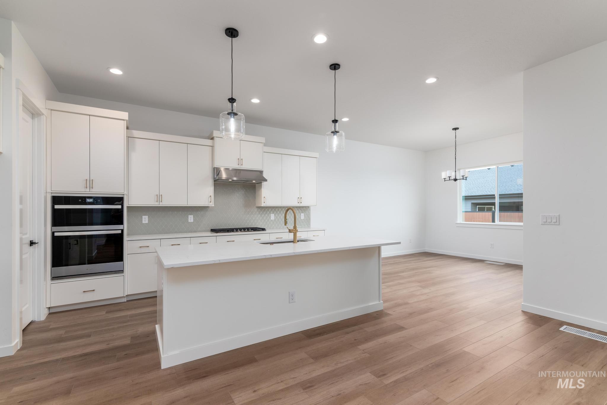 Kitchen featuring pendant lighting, backsplash, stainless steel appliances, white cabinets, and recessed lighting