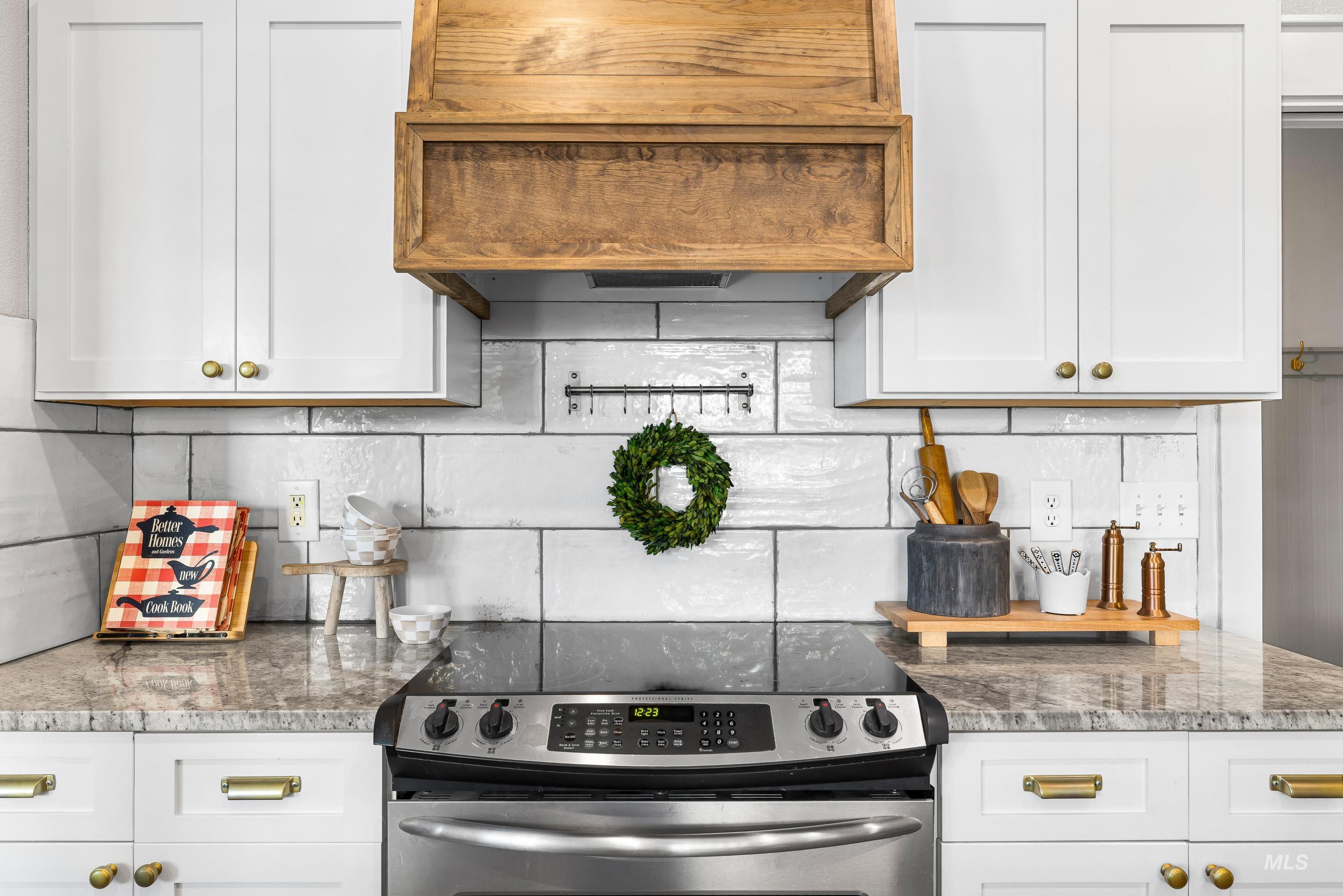 Kitchen with stainless steel electric range oven, white cabinets, custom exhaust hood, and light stone counters