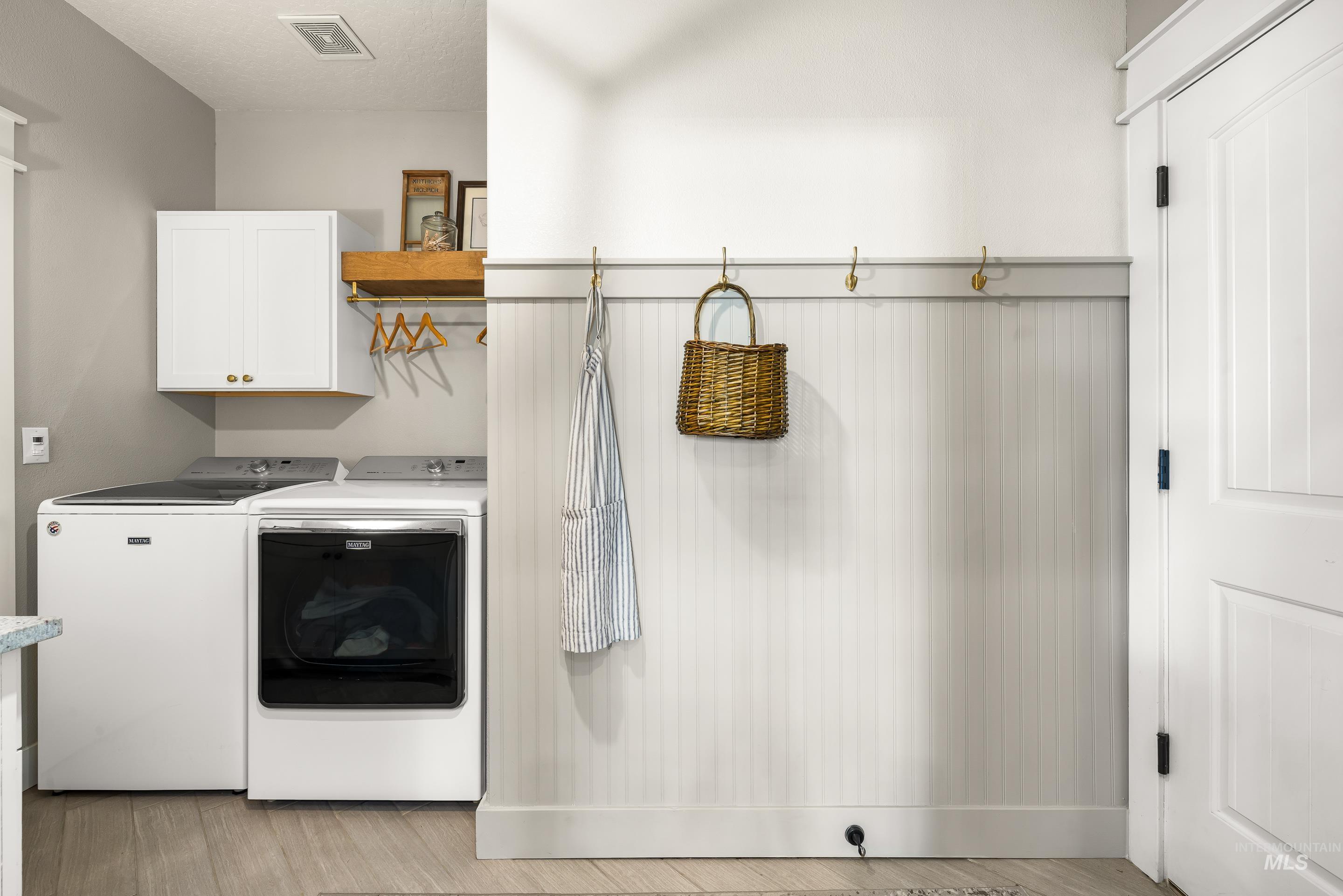 Laundry room featuring cabinet space, separate washer and dryer, and light wood finished floors