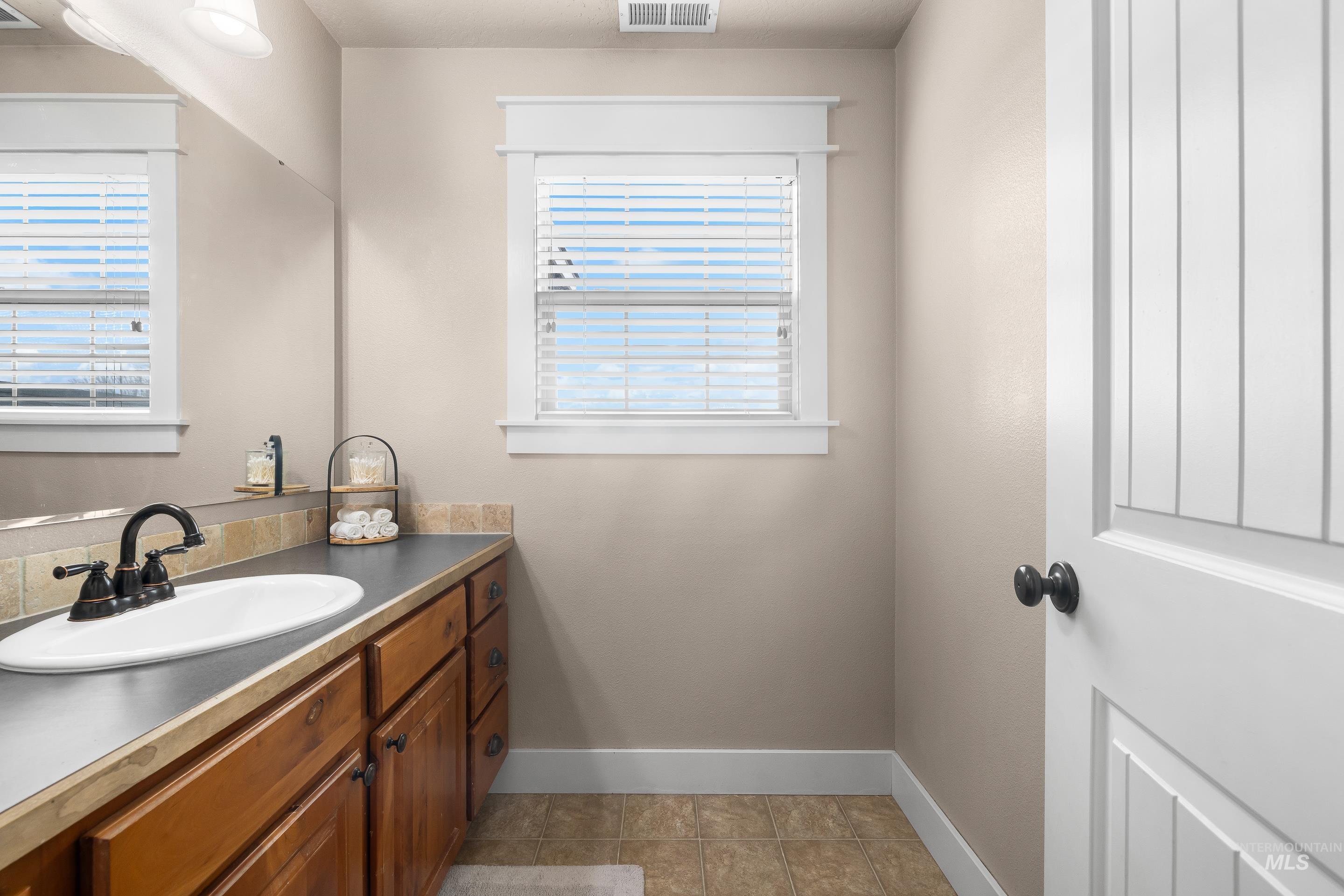 Bathroom featuring vanity, light tile patterned floors, and healthy amount of natural light