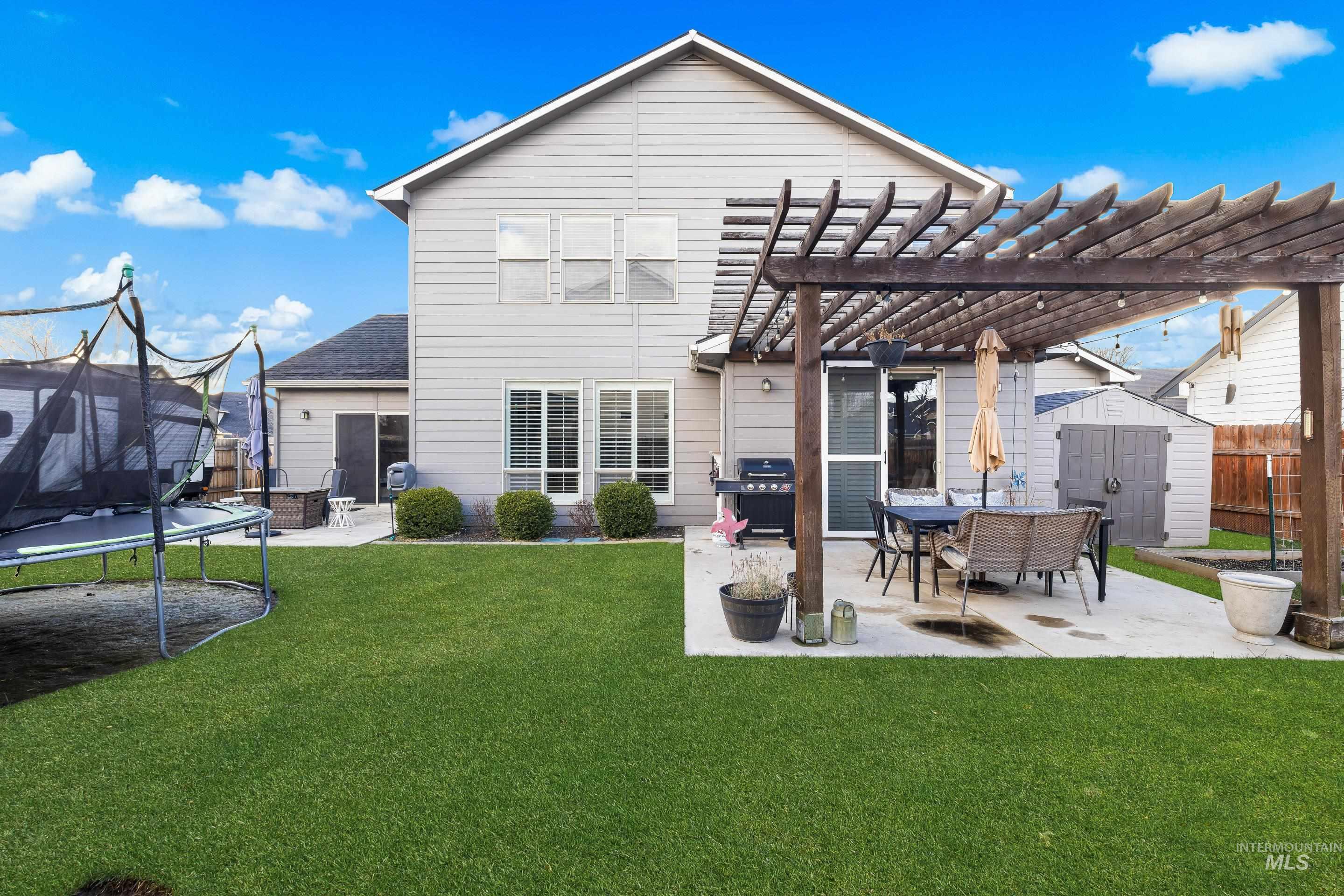 Back of property featuring a trampoline, a storage shed, a patio area, and a pergola