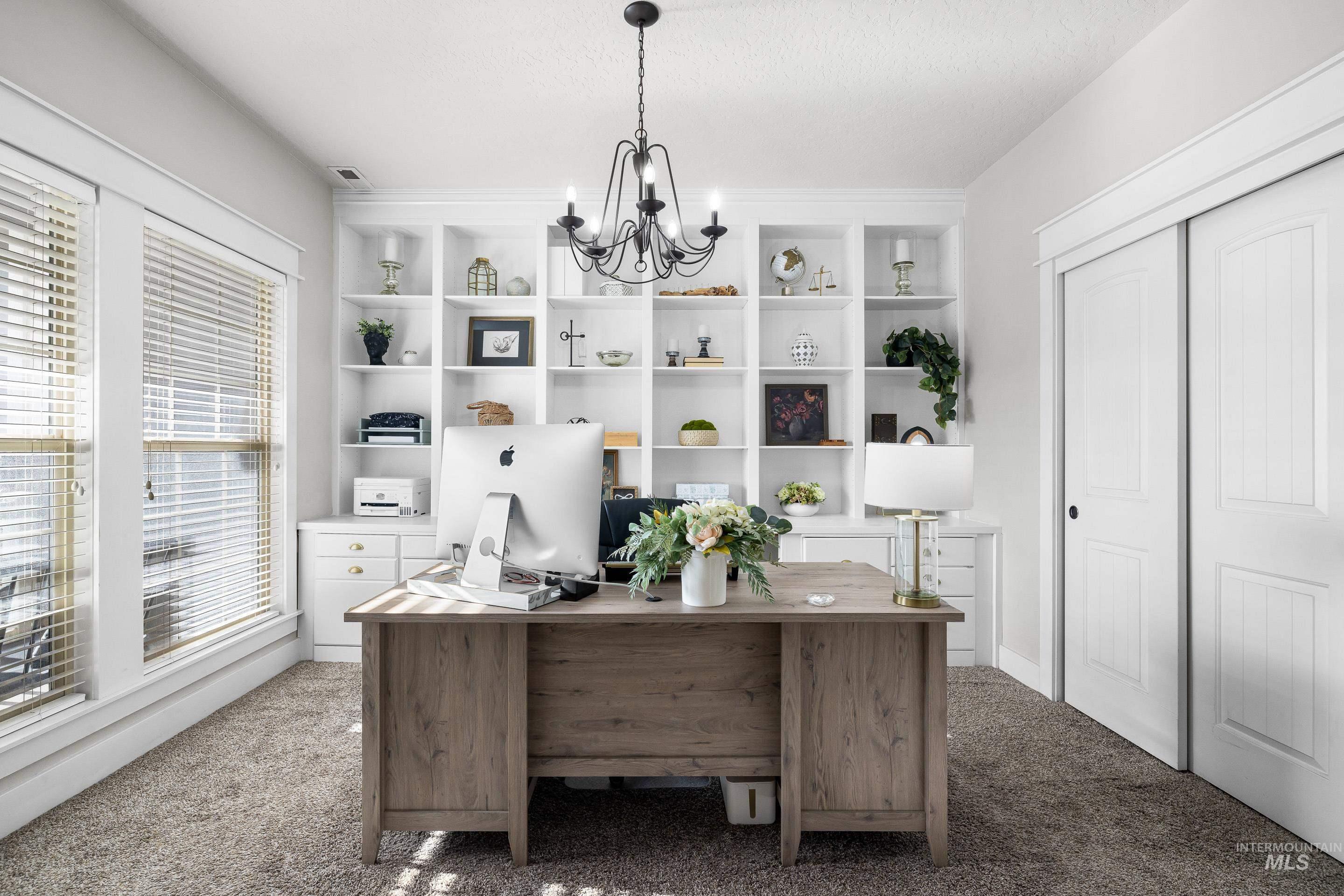 Carpeted home office with a chandelier