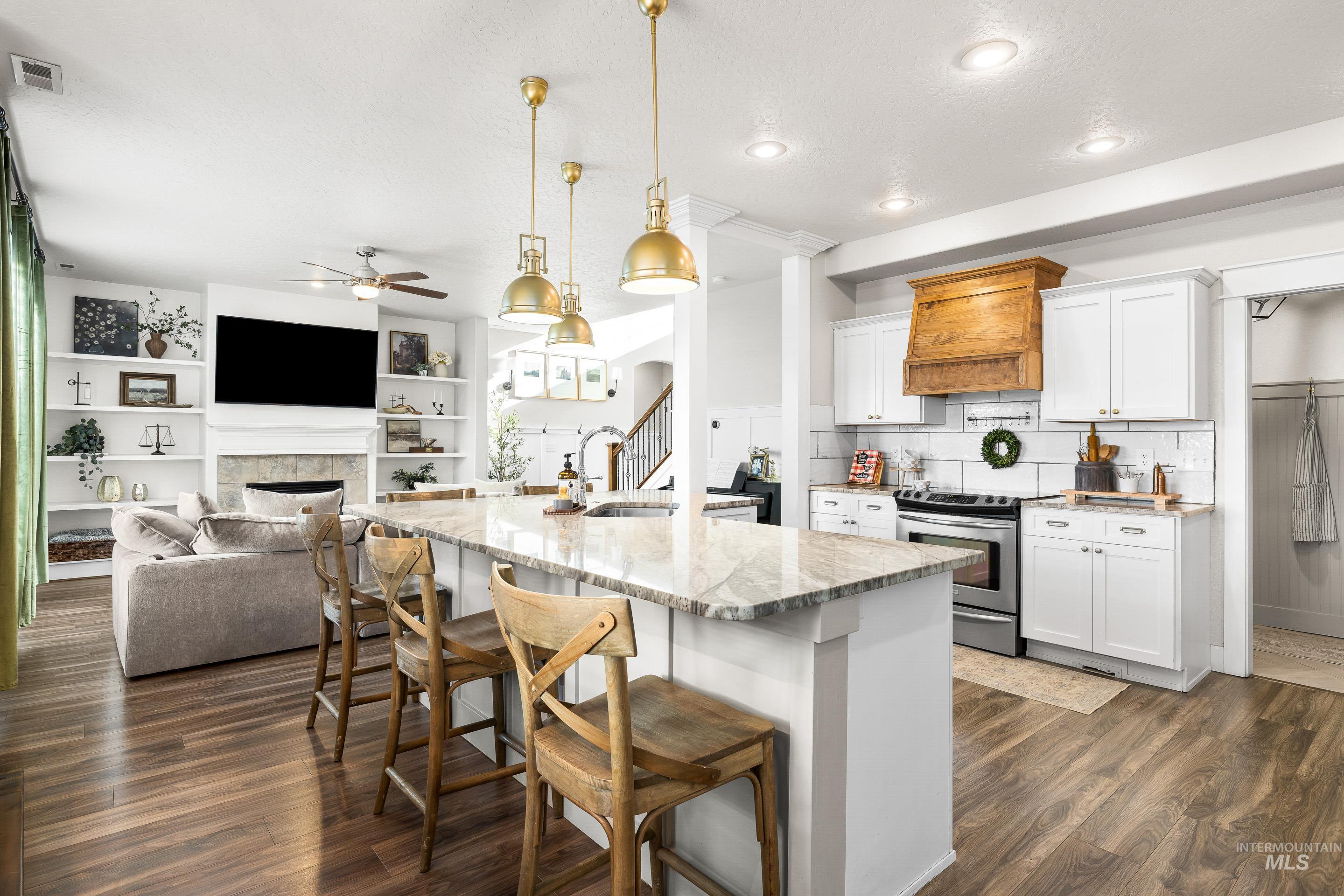 Kitchen featuring a kitchen breakfast bar, light stone counters, white cabinetry, built in features, and stainless steel electric range