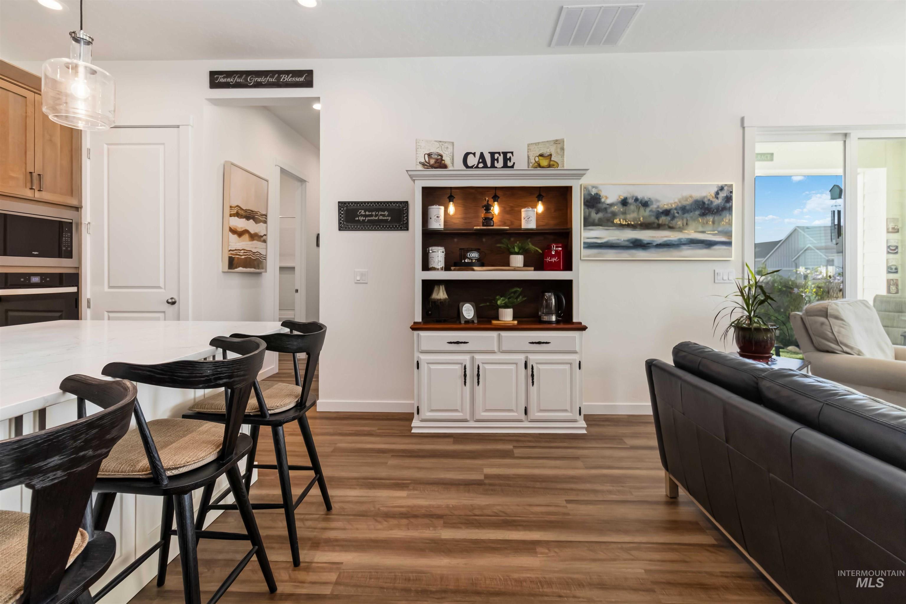 Bar featuring wood-style flooring, built in oven and gas cook top, recessed lighting, hanging modern farm style light fixtures and stainless steel microwave