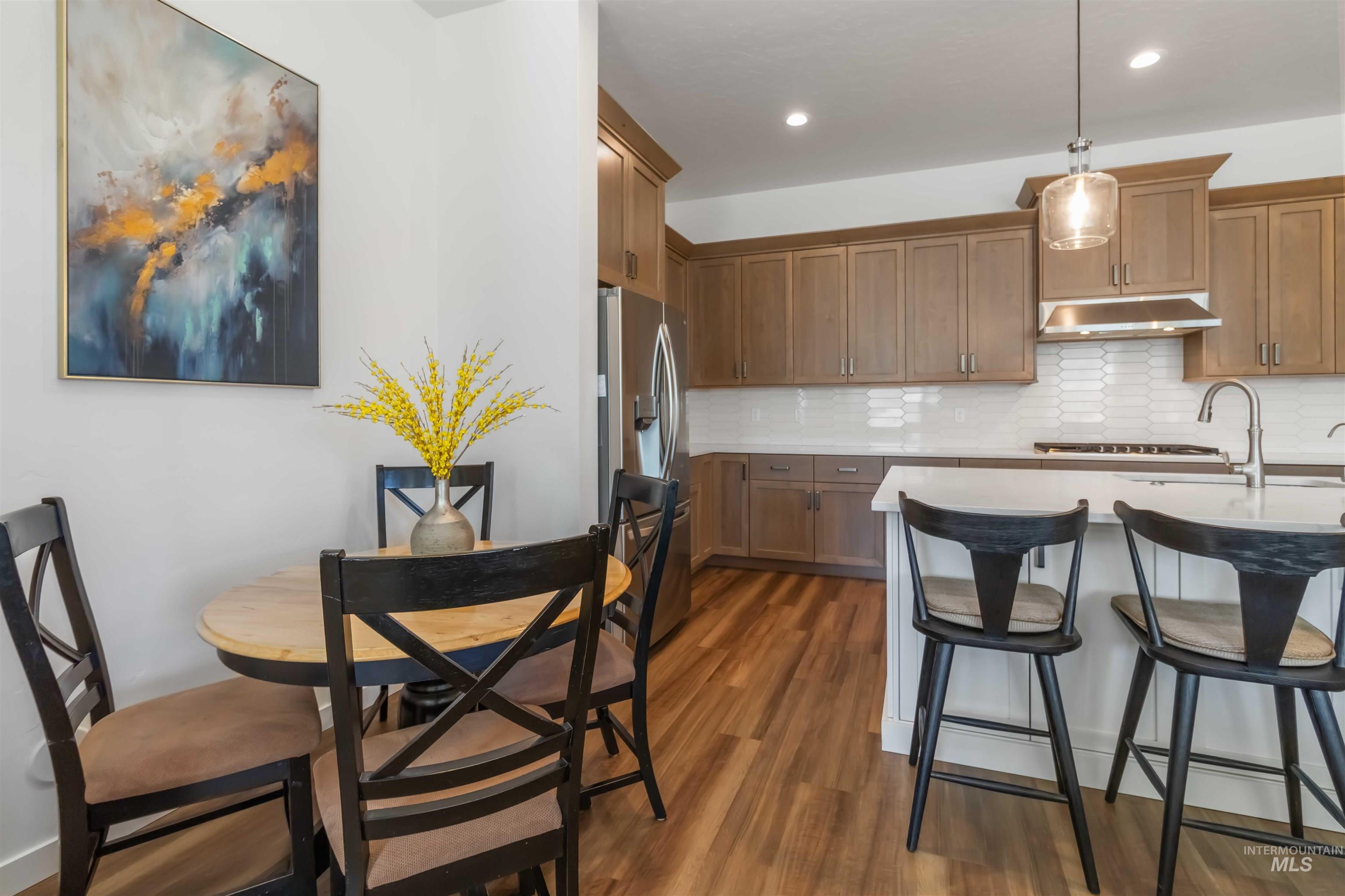Kitchen with warm toned wood cabinetry, decorative backsplash, wood flooring, and a kitchen breakfast bar