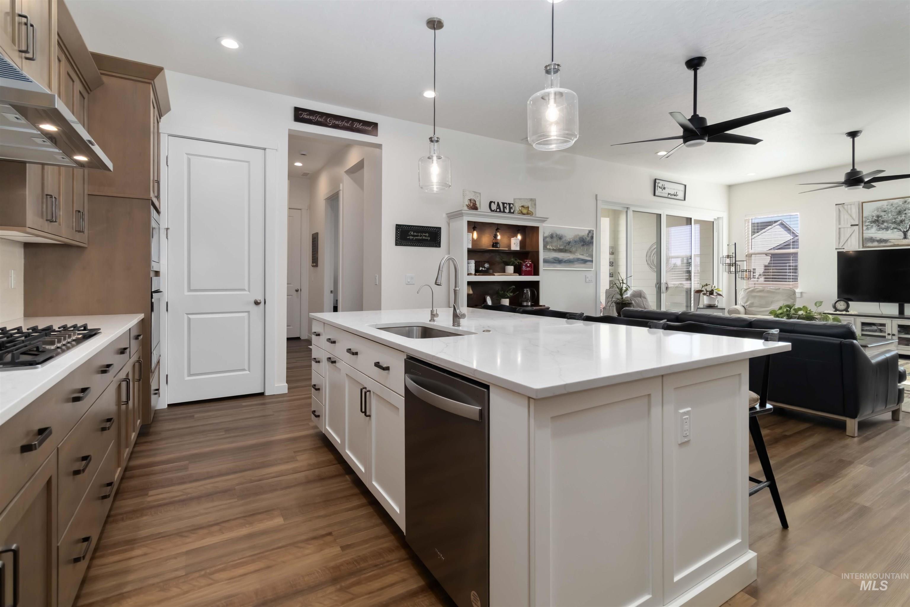 Kitchen with open floor plan, a ceiling fan, decorative light fixtures, appliances with stainless steel finishes, and wood finished floors