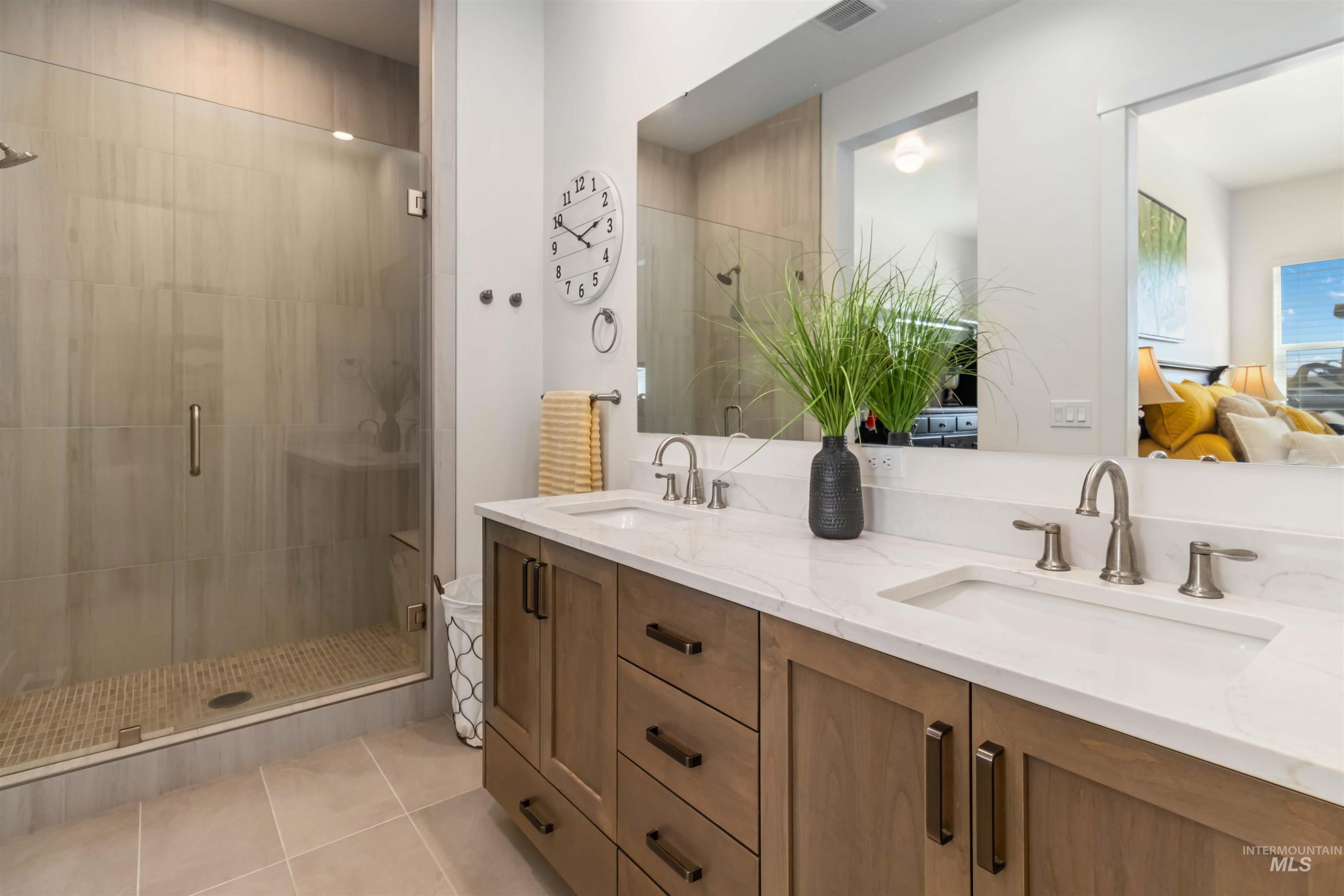 Ensuite bathroom with a large walk in shower and bench, double vanity, and light tile patterned floors