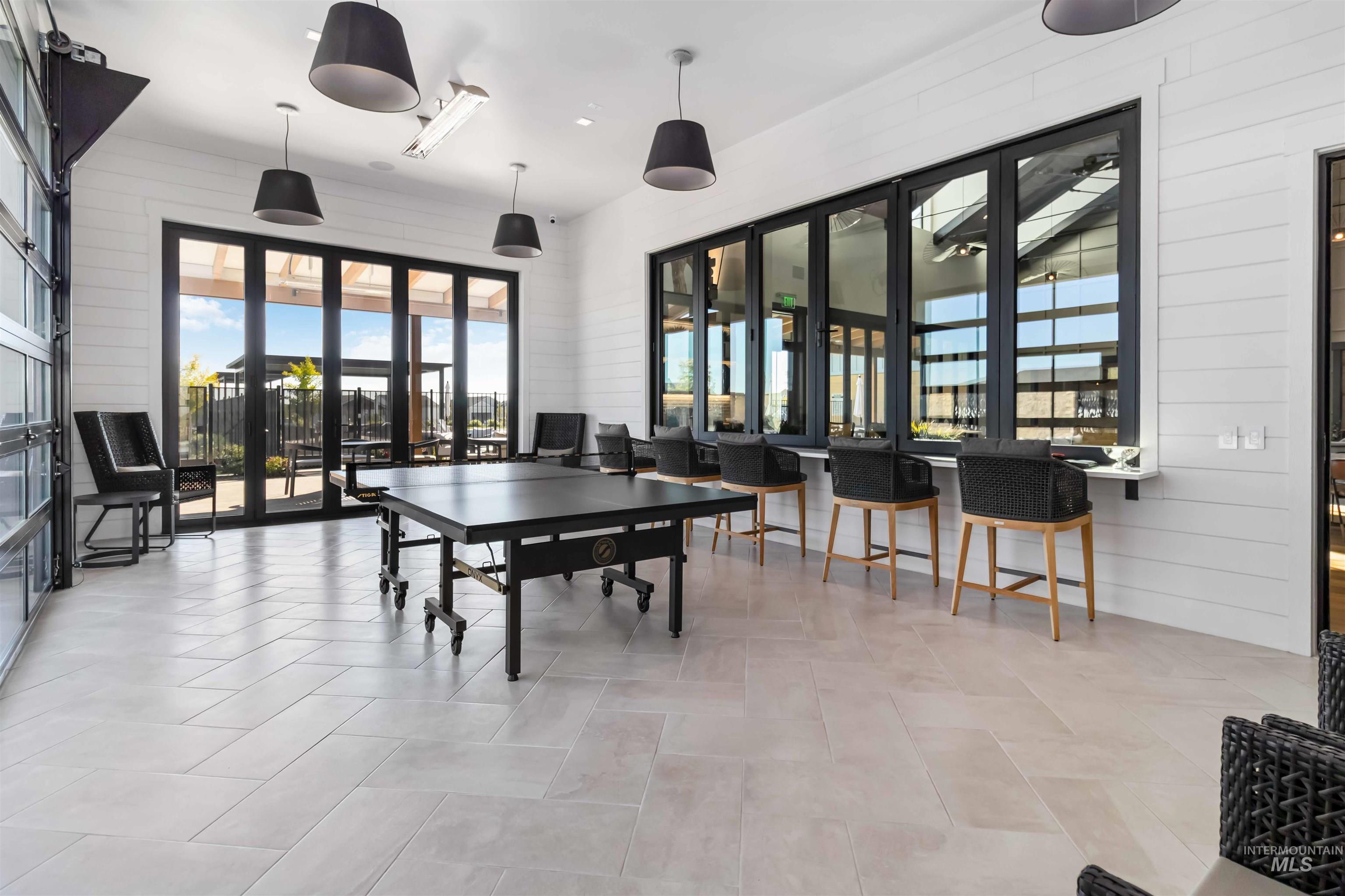 Game room featuring spectacular architecture! Wood walls, impressive amount of natural light, windows and doors open for added community experience.