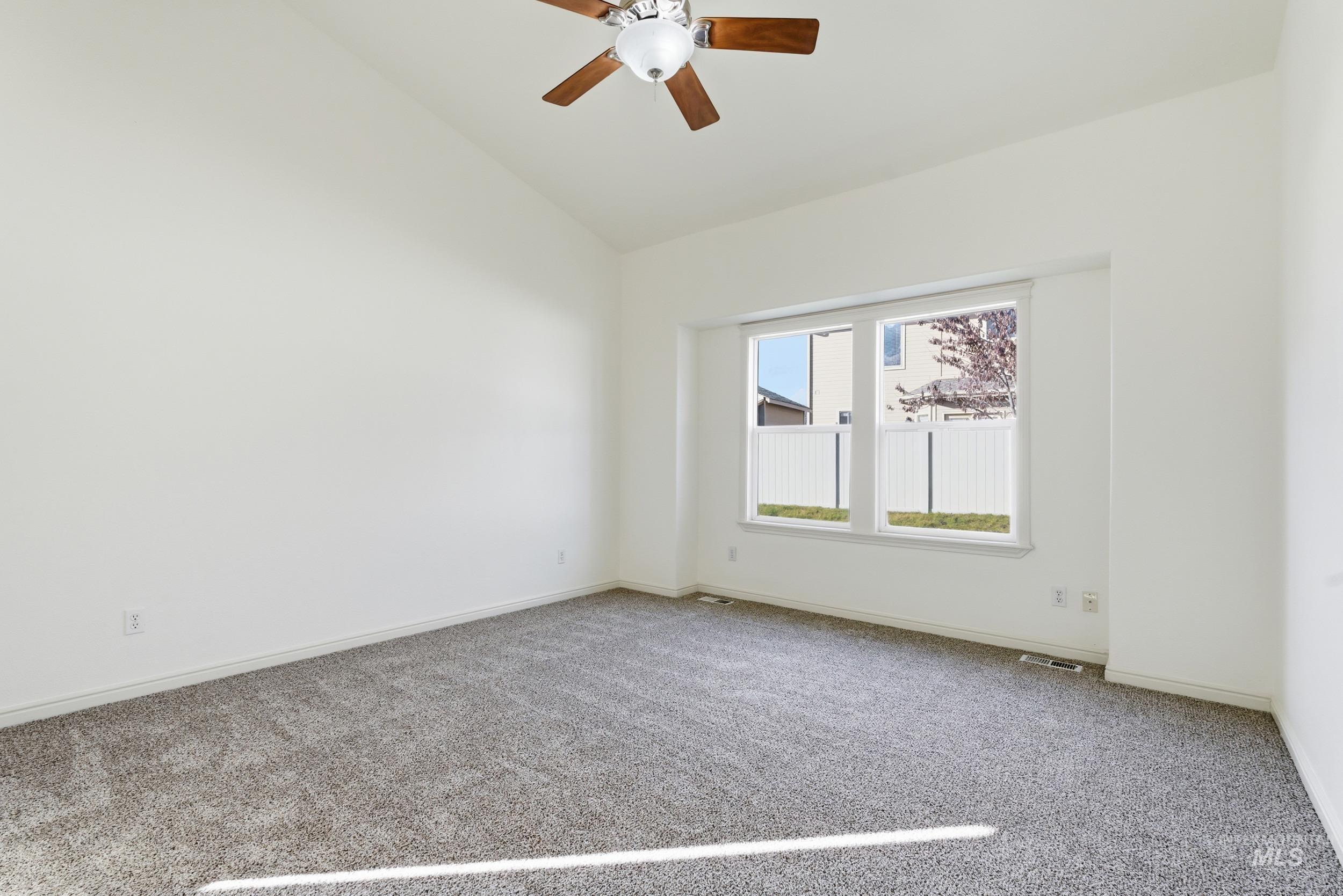 Carpeted spare room with vaulted ceiling and a ceiling fan